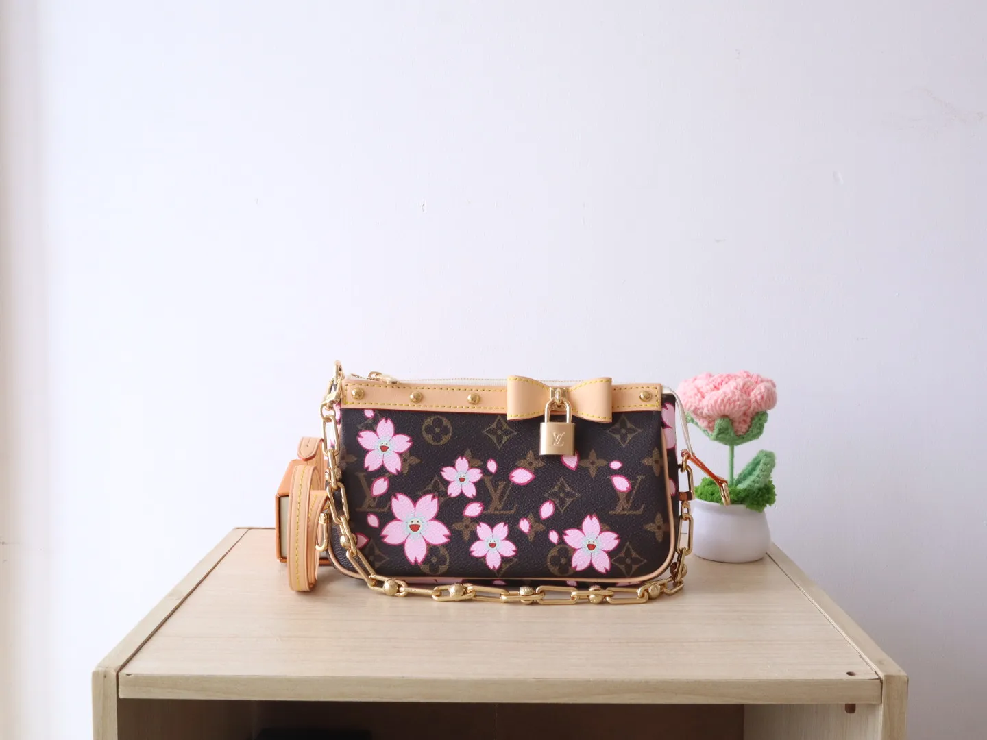 M13666 Cherry Blossom 🌟P740 This Pochette Accessoires handbag is made of classic Monogram canvas with the bright Cherry Blossom pattern written by Takashi Murakami, which expresses the distinctive elements of the Louis Vuitton x Takashi Murakami replica series in a playful style. A leather bow and LV-engraved padlock accent the upper edge, while dazzling studs and a detachable chain add a touch of irreverence. 13 x 4 x 22 cm