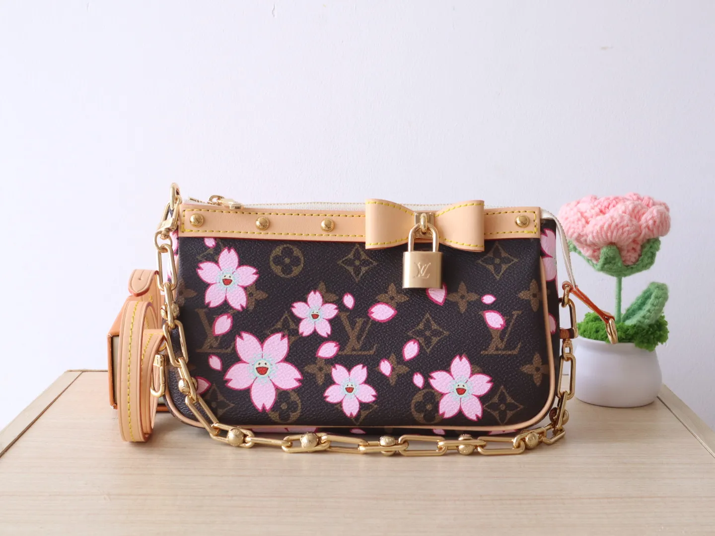 M13666 Cherry Blossom 🌟P740 This Pochette Accessoires handbag is made of classic Monogram canvas with the bright Cherry Blossom pattern written by Takashi Murakami, which expresses the distinctive elements of the Louis Vuitton x Takashi Murakami replica series in a playful style. A leather bow and LV-engraved padlock accent the upper edge, while dazzling studs and a detachable chain add a touch of irreverence. 13 x 4 x 22 cm