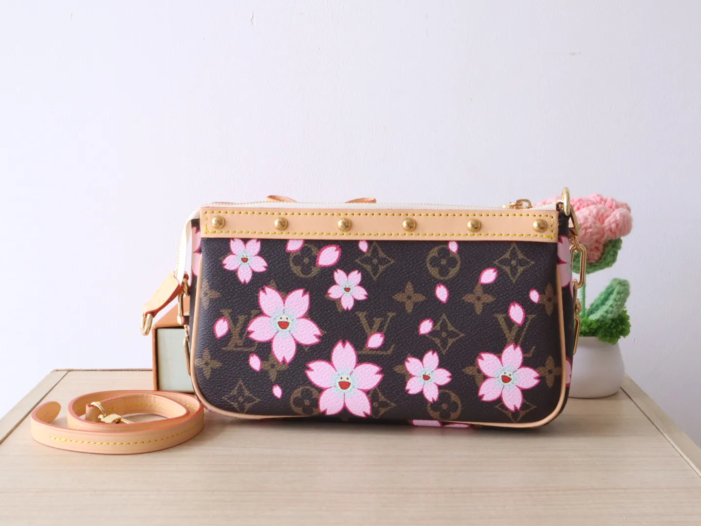 M13666 Cherry Blossom 🌟P740 This Pochette Accessoires handbag is made of classic Monogram canvas with the bright Cherry Blossom pattern written by Takashi Murakami, which expresses the distinctive elements of the Louis Vuitton x Takashi Murakami replica series in a playful style. A leather bow and LV-engraved padlock accent the upper edge, while dazzling studs and a detachable chain add a touch of irreverence. 13 x 4 x 22 cm
