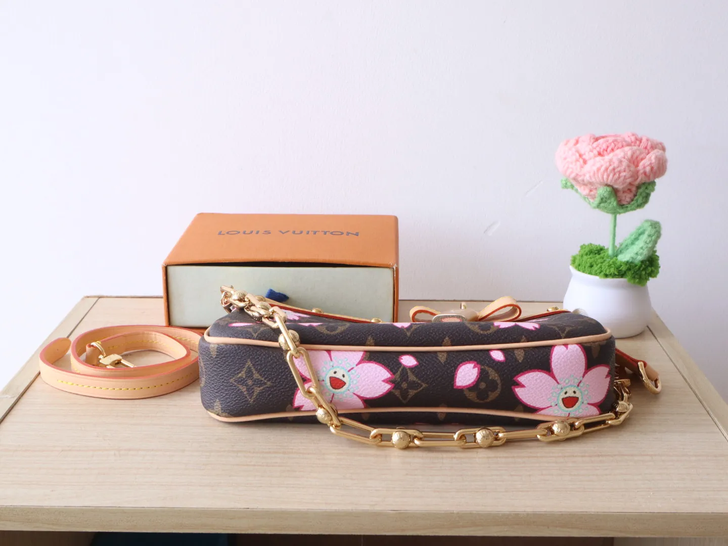 M13666 Cherry Blossom 🌟P740 This Pochette Accessoires handbag is made of classic Monogram canvas with the bright Cherry Blossom pattern written by Takashi Murakami, which expresses the distinctive elements of the Louis Vuitton x Takashi Murakami replica series in a playful style. A leather bow and LV-engraved padlock accent the upper edge, while dazzling studs and a detachable chain add a touch of irreverence. 13 x 4 x 22 cm