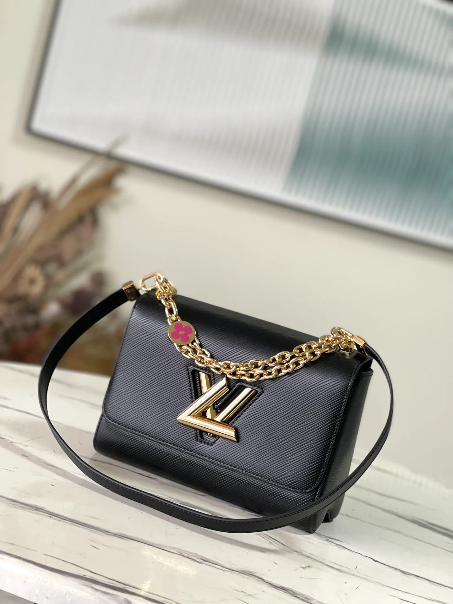 💰1160 (First-Grade Leather) Top Original M21606 Black This Twist medium handbag incorporates an enamel Monogram flower into the double chain, which can be used as a subtle embellishment or connected to the shoulder strap to achieve more styling possibilities. Epi grained leather body with smooth leather trim and lining. Dimensions: 23 x 17 x 9.5 cm