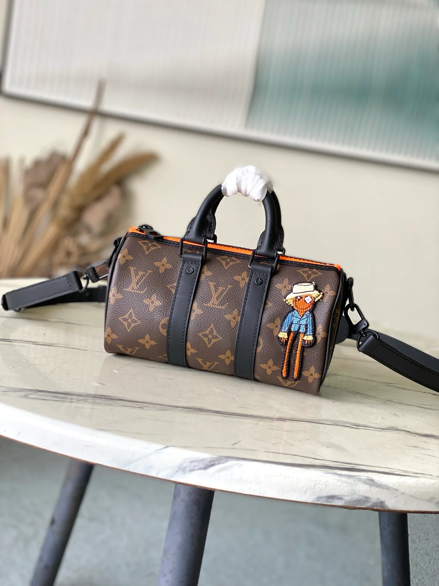 💰840 Top Original M80201 This Keepall Nano men's handbag is a compact version of the brand's original soft travel bag launched in 1930, combining Monogram canvas with black matte leather. A pop of neon orange next to the edge of the zipper makes this classic look pop. The embroidered patches feature cartoon characters from the “Zoom with friends” animated short created by menswear artistic director Virgil Abloh. Dimensions: 12 x 21 x 9 cm