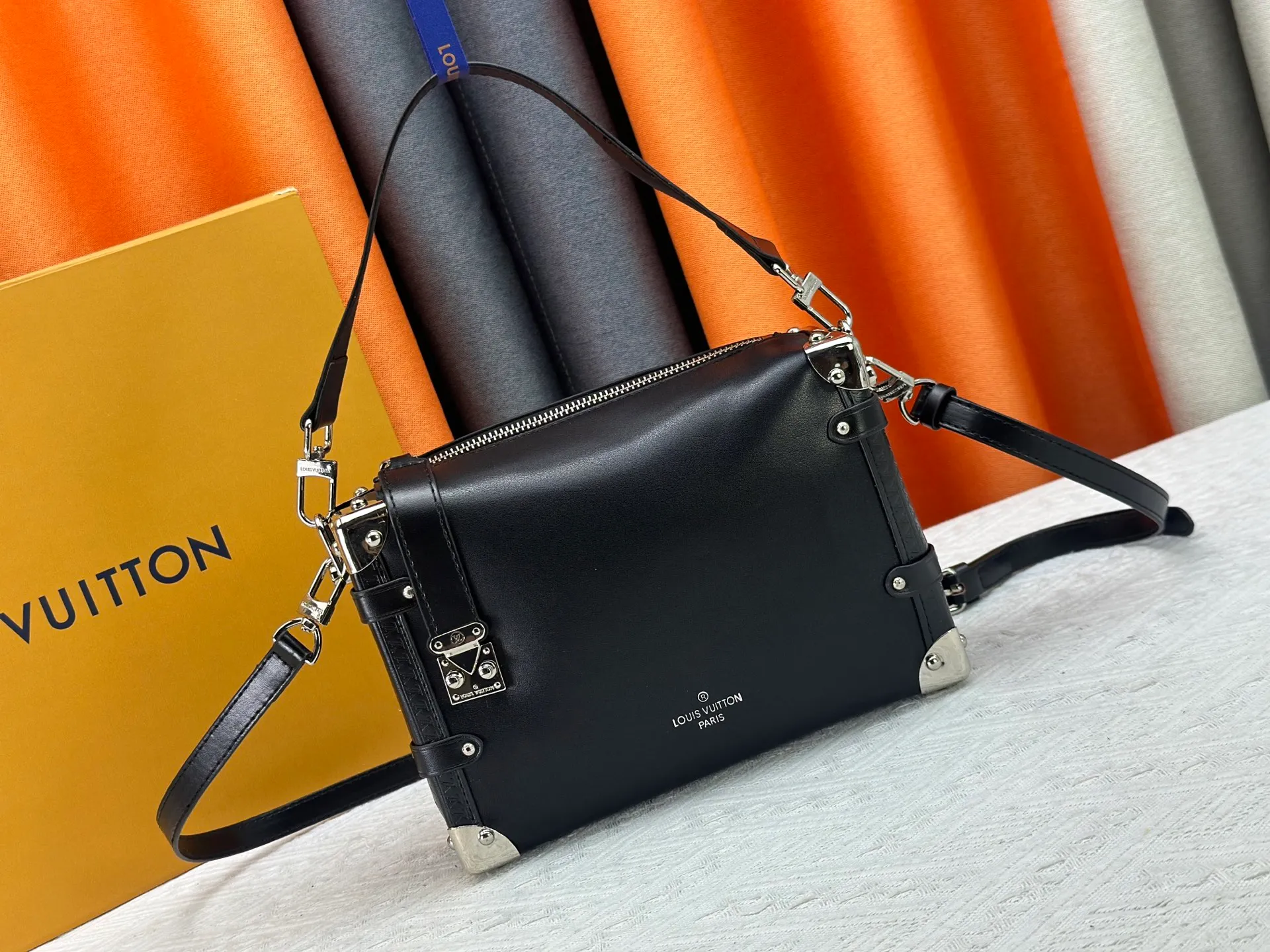 P300 M15195 M46358 This Side Trunk Vibe handbag reimagines the brand's classic Side Trunk silhouette with an avant-garde design, inspired by Louis Vuitton's traditional travel trunks. Crafted from smooth glossy Vibe textured cow leather, it features a leather-covered rivet frame and metal S-lock closure for a rock-and-roll style. Thanks to the multiple designs of the detachable chain, detachable leather handle and adjustable leather shoulder strap, it provides a variety of carrying options. Dimensions: 23.5x16x8.5cm