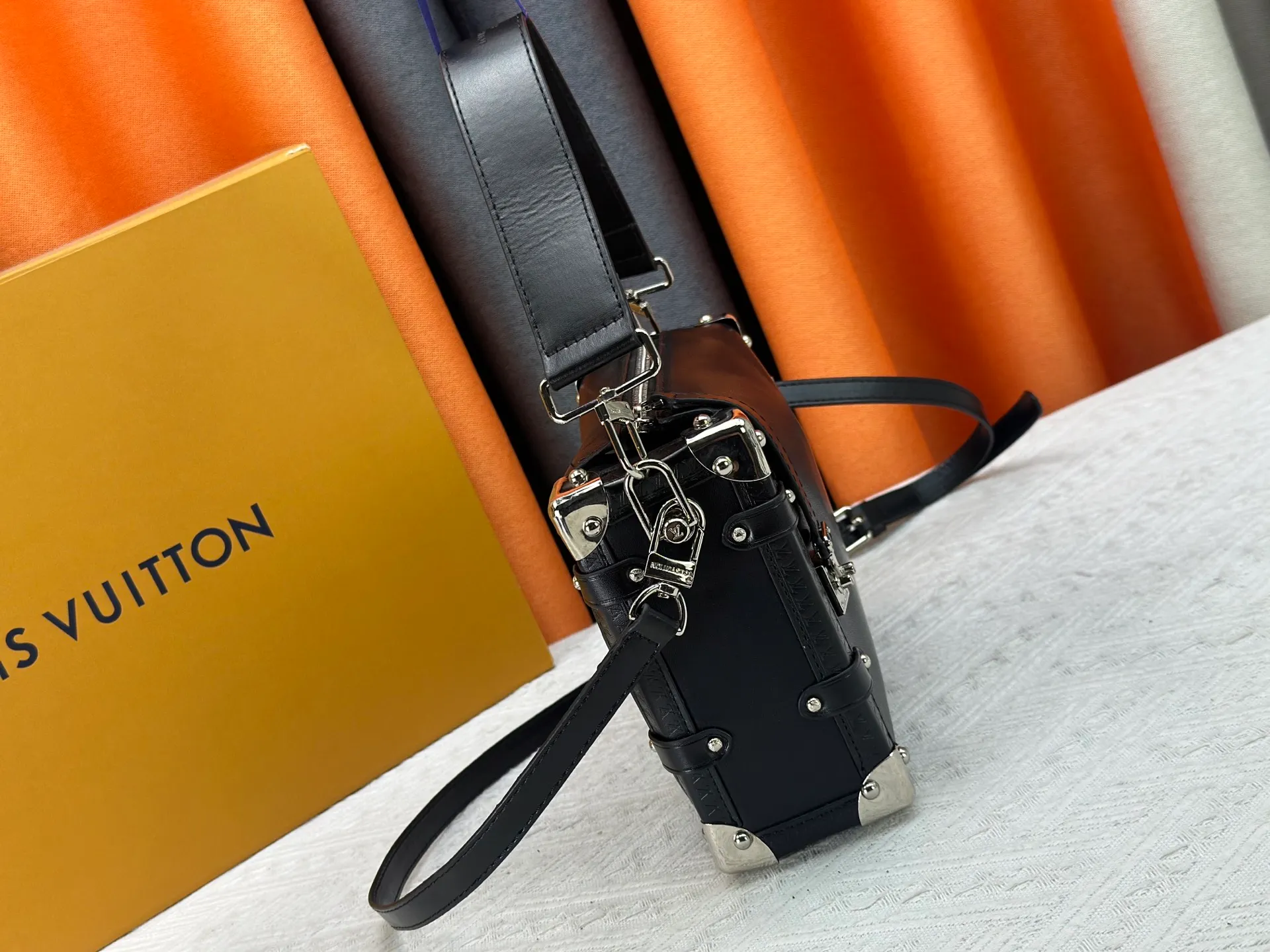 P300 M15195 M46358 This Side Trunk Vibe handbag reimagines the brand's classic Side Trunk silhouette with an avant-garde design, inspired by Louis Vuitton's traditional travel trunks. Crafted from smooth glossy Vibe textured cow leather, it features a leather-covered rivet frame and metal S-lock closure for a rock-and-roll style. Thanks to the multiple designs of the detachable chain, detachable leather handle and adjustable leather shoulder strap, it provides a variety of carrying options. Dimensions: 23.5x16x8.5cm