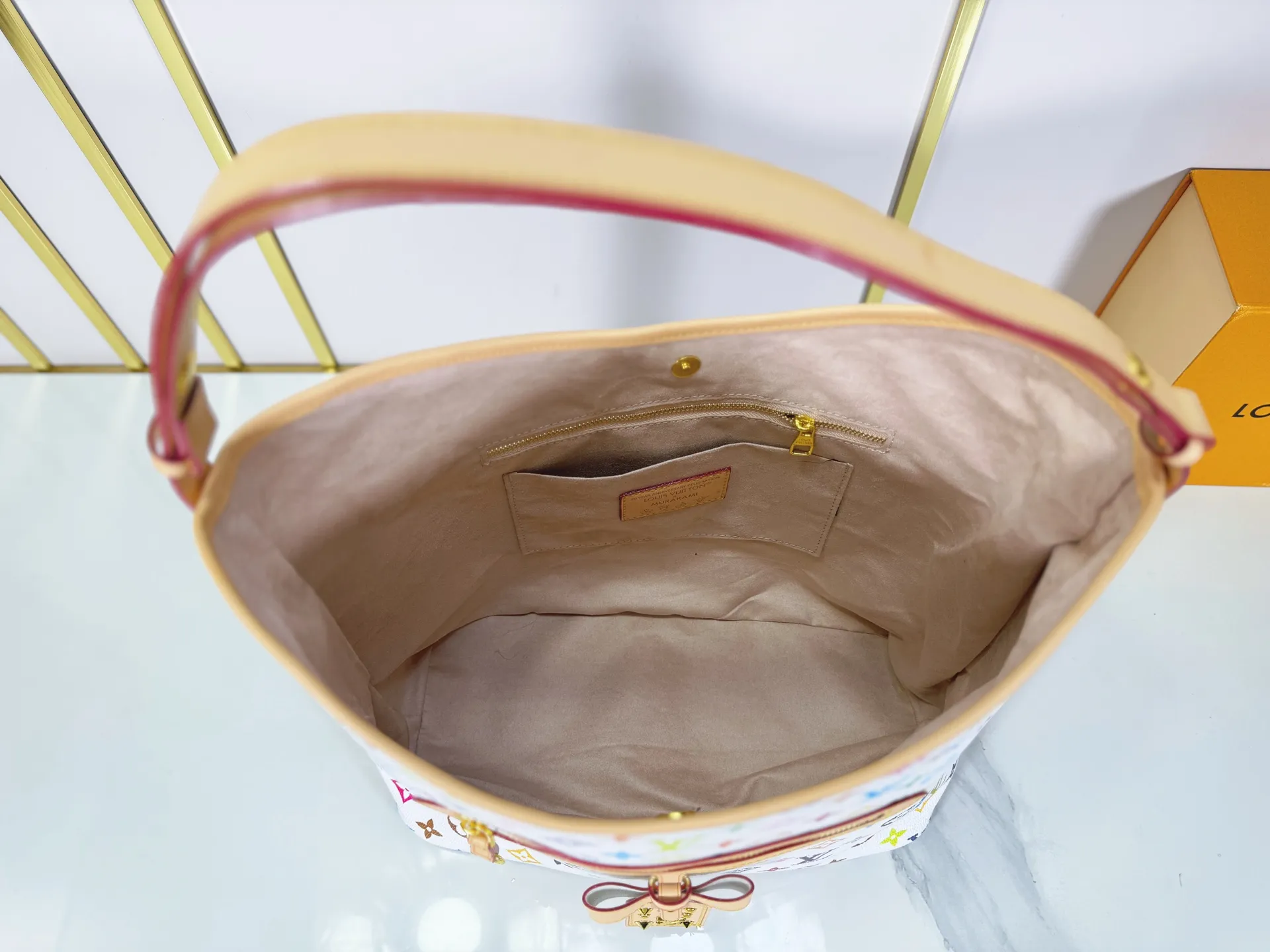 P260 M27582 upgraded from the original version, the iconic design of the Murakami series. The bag is made of smooth cotton-paved leather and is embossed with the brand's Monogram pattern. The iconic thick chain strap is paired with gold-tone hardware, and the wide non-detachable textile shoulder strap can be carried in different ways. This versatile style is large enough to hold a laptop and features a removable zip pocket. Dimensions: 32.5x32.5x15cm