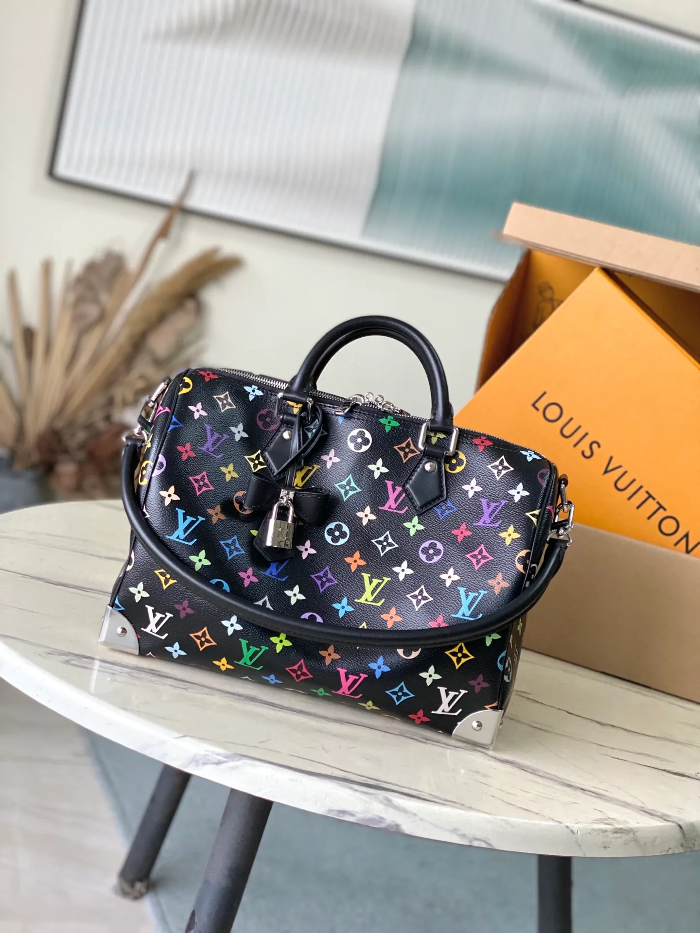 💰1180 Top Original M13257 This SpeedySoft30 handbag is made of soft coated canvas, and the full-length Monogram pattern is traced in colorful rainbow tones, highlighting the smart style of the Louis Vuitton x Murakami reissue series. The Toron handle and detachable shoulder strap are constructed of cow leather, the metal corners recall classic luggage elements, and the bow-shaped key bag and padlock add brand touches. Dimensions: 30 × 21 × 17 cm