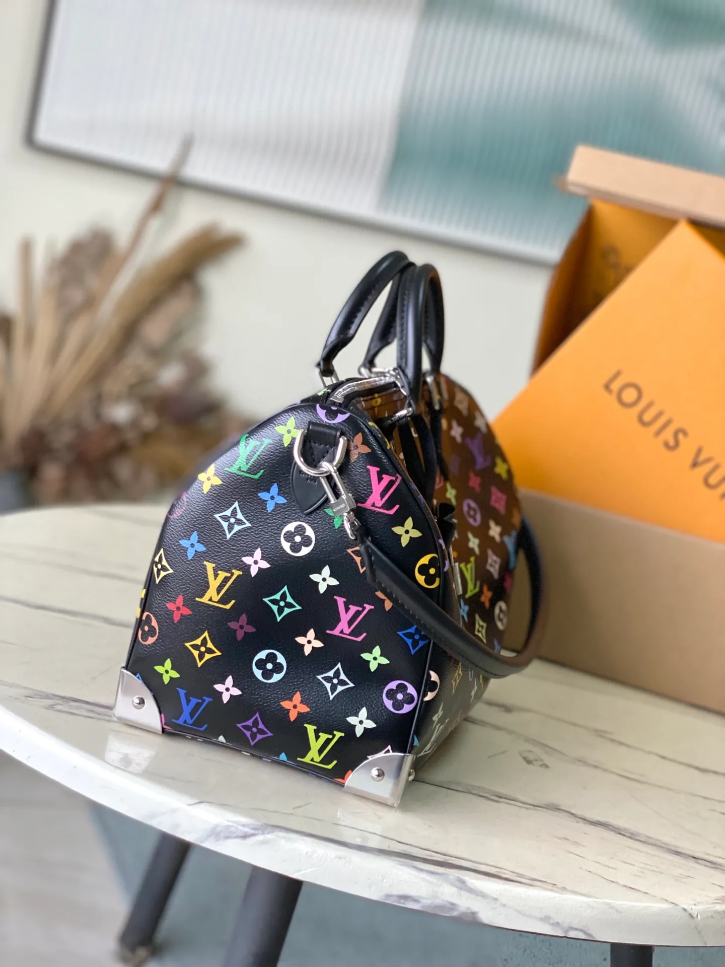 💰1180 Top Original M13257 This SpeedySoft30 handbag is made of soft coated canvas, and the full-length Monogram pattern is traced in colorful rainbow tones, highlighting the smart style of the Louis Vuitton x Murakami reissue series. The Toron handle and detachable shoulder strap are constructed of cow leather, the metal corners recall classic luggage elements, and the bow-shaped key bag and padlock add brand touches. Dimensions: 30 × 21 × 17 cm