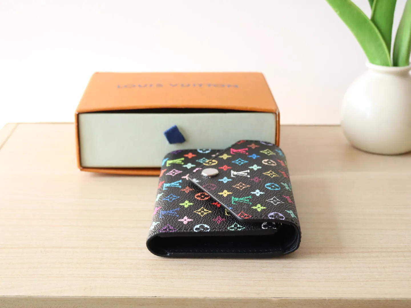 14163 Tri-Color Tri-fold Wallet🌟P90 This replica version of the Victorine wallet from the Louis Vuitton x Murakami series is small and exquisite. The colorful Monogram pattern reinterprets Louis Vuitton's classic logo with the famous rainbow tones of Japanese artist Takashi Murakami. The wallet is made of coated canvas with fine cowhide lining and silver-tone hardware. It has a zippered coin compartment and multiple interior compartments for banknotes and business cards. 12 x 9.5 x 2.5 cm (length x height x width)