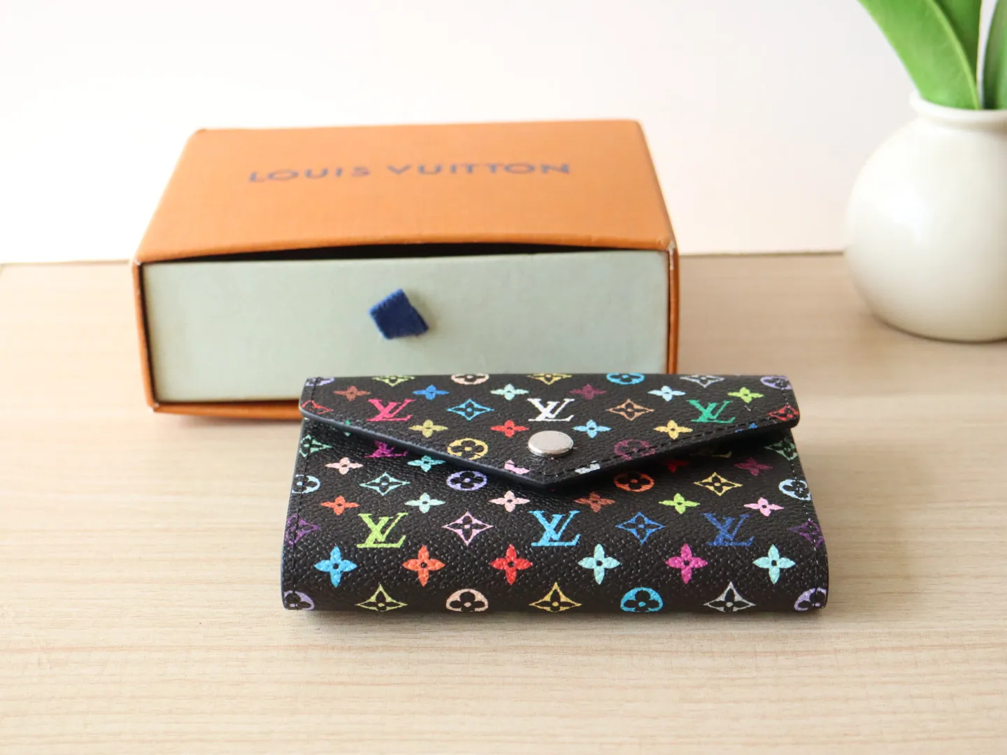 14163 Tri-Color Tri-fold Wallet🌟P90 This replica version of the Victorine wallet from the Louis Vuitton x Murakami series is small and exquisite. The colorful Monogram pattern reinterprets Louis Vuitton's classic logo with the famous rainbow tones of Japanese artist Takashi Murakami. The wallet is made of coated canvas with fine cowhide lining and silver-tone hardware. It has a zippered coin compartment and multiple interior compartments for banknotes and business cards. 12 x 9.5 x 2.5 cm (length x height x width)