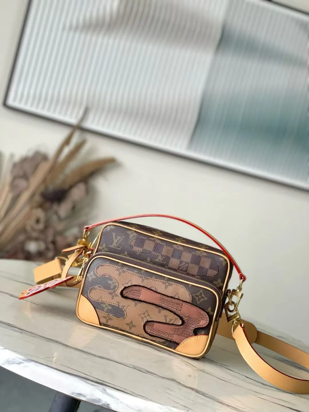 💰1280 Top Original M26068 This Nil crossbody bag is made of Monogram canvas body with Damier and Monogram Reverse canvas patches, creating an elegant collage effect. The spacious main compartment and zippered front pocket ensure easy access, while the removable top handle and shoulder strap allow for multiple carry options. 17.5 x 11 x 25 cm (height x width x length)