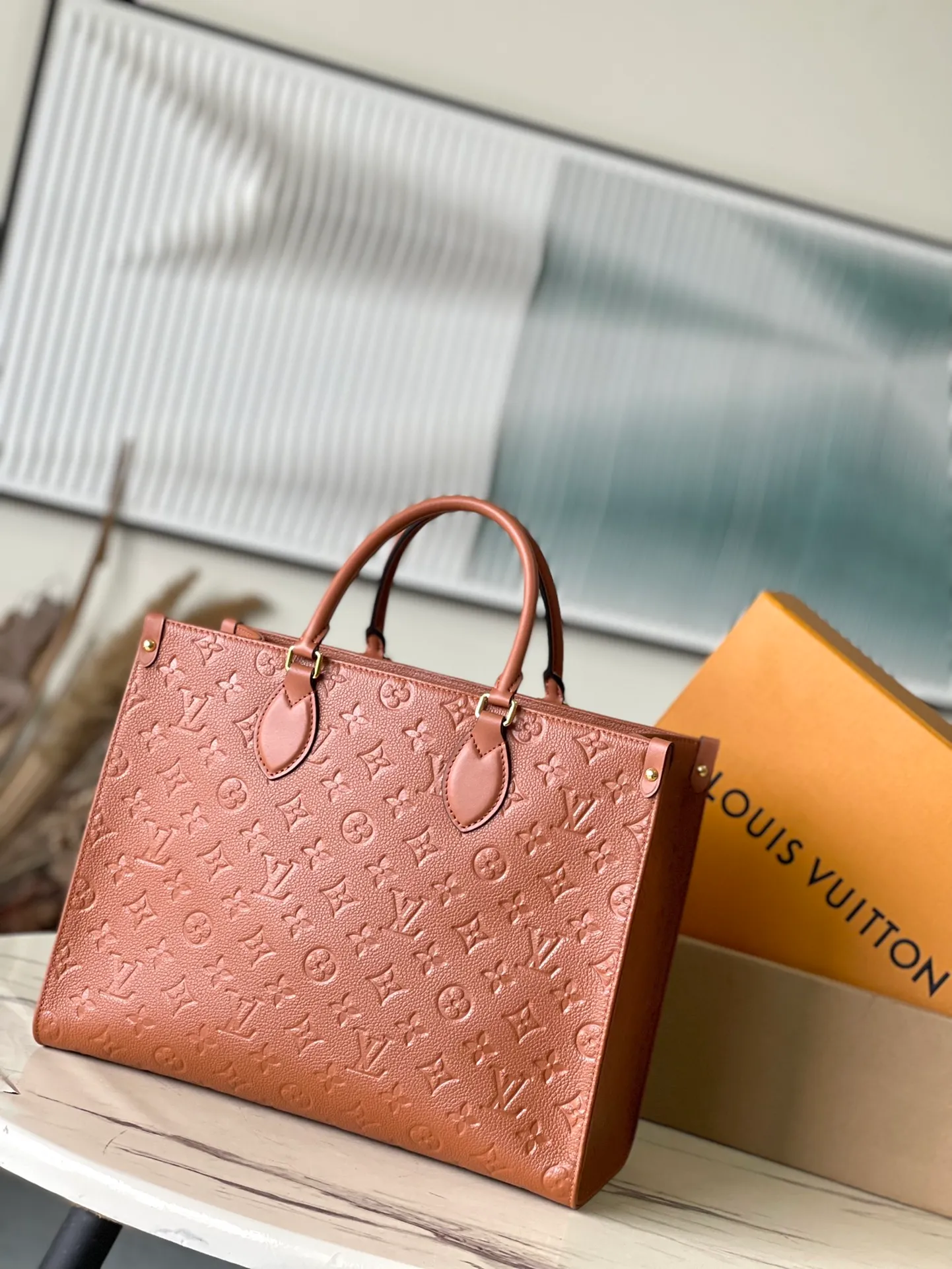 💰1140 (top-grain leather) Top-quality original order M12775 This medium-sized OnTheGo handbag is inspired by retro hard cases. The brand's iconic Monogram Empreinte leather is dyed with rich colors and matched with exquisite metal parts. The ample structure can accommodate a 13-inch laptop, and there are multiple inner pockets for convenient storage of items. Long and short handles enable multiple carrying methods. Dimensions: 35 × 27 × 14 cm