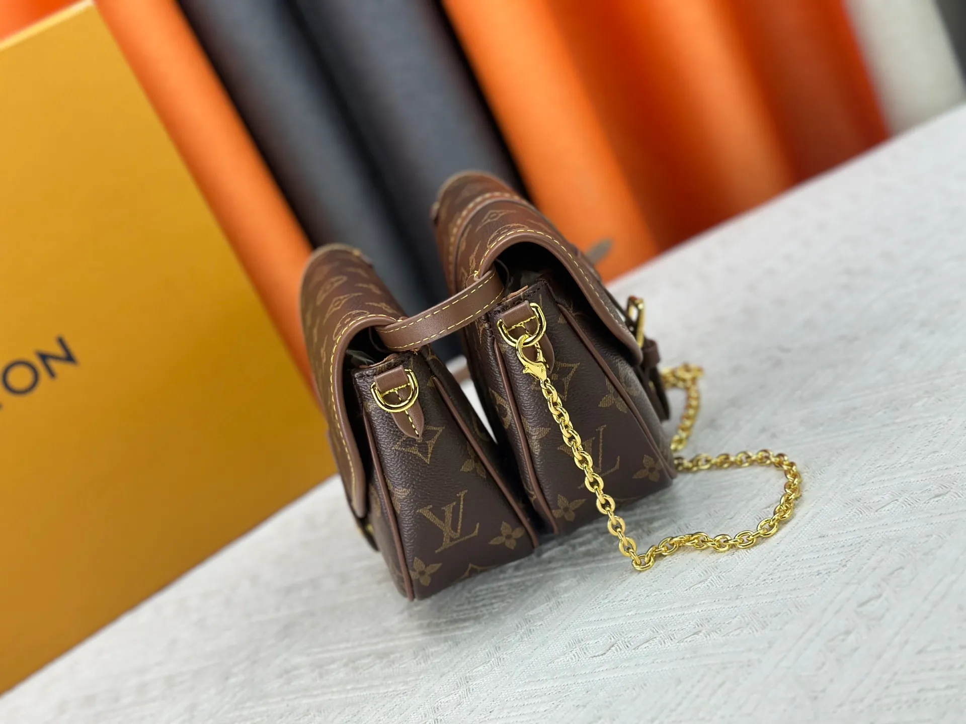 P300 upgrades the original M26592 2025 autumn and winter new Duo BB handbag with a new silhouette, integrating chic design with modern style. This fun accessory reinterprets the Saumur bag's classic shape in the brand's signature Monogram canvas with contrasting calfskin trim and an adjustable shoulder strap. It can be worn around the waist, with two compartments on either side of the hip, or it can be split into two separate handbags. Metal parts add a refined touch. Dimensions: 19 x 14 x 6 (cm) ((length x height x width)