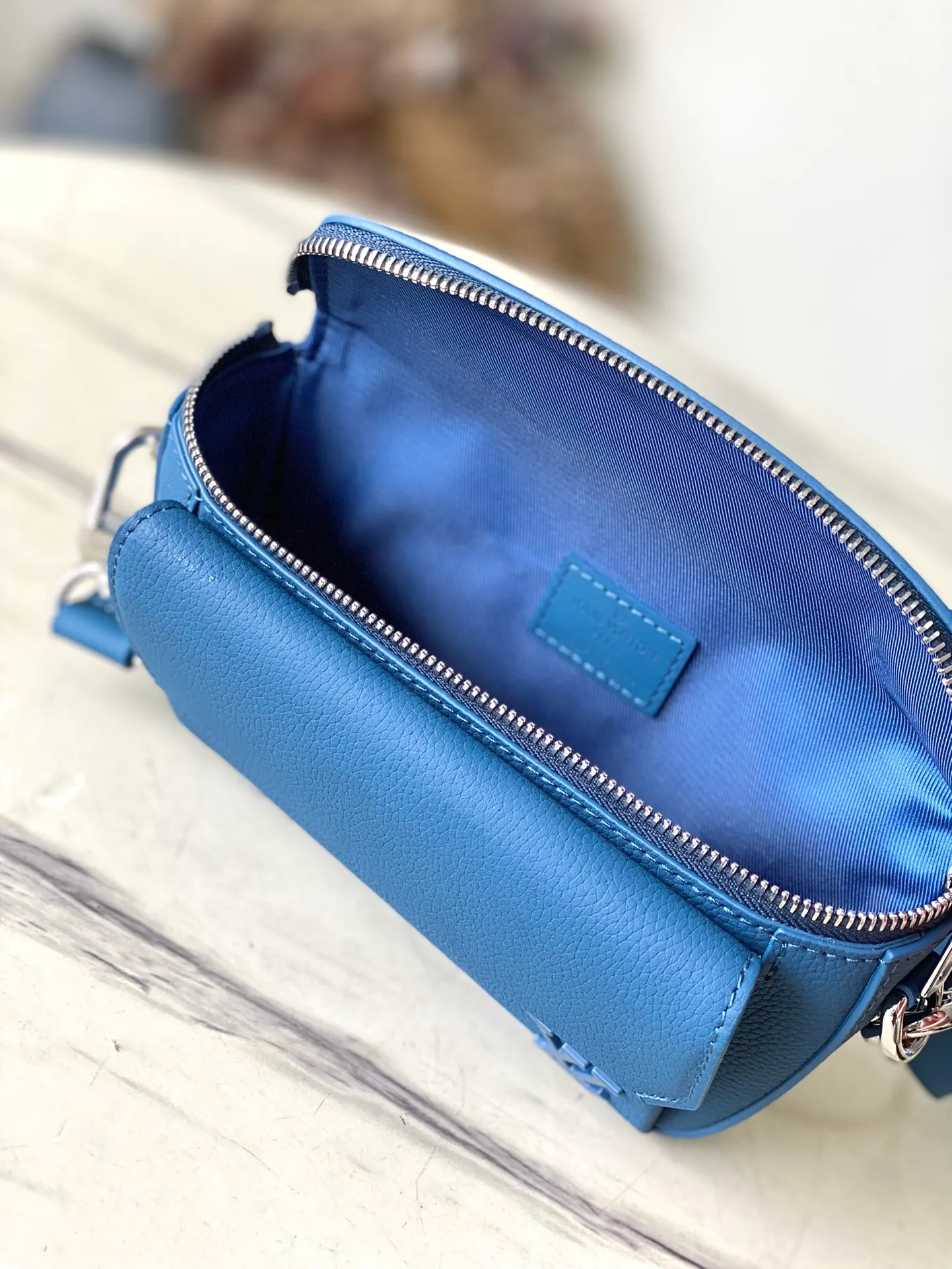 💰940 (top layer leather) top original order M83563 blue. This Pilot mini handbag is made of grained cow leather with a round shape, providing a trendy choice for daily travel. A zippered main compartment ensures secure storage, and a front pocket provides easy access to small items like your phone or keys. Detachable shoulder strap allows for comfortable shoulder or cross-body wear. Dimensions: 20 × 12 × 5,5 cm