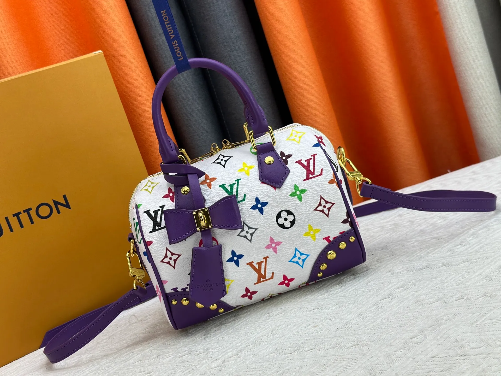 P260 upgraded original M58953 M46234 M46222 Speedy Bandoulière 20 handbag is made of soft coated canvas, and the full-length Monogram pattern is traced in colorful rainbow tones, highlighting the smart style of the Louis Vuitton x Murakami reissue series. The Toron handle and detachable shoulder strap are constructed of cow leather, the metal corners recall classic luggage elements, and the bow-shaped key bag and padlock add brand touches. Dimensions: 20.5 x 13.5 x 12.0 cm (length x height x width)