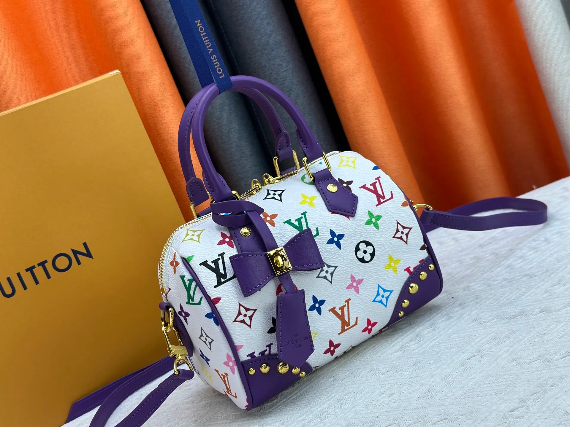 P260 upgraded original M58953 M46234 M46222 Speedy Bandoulière 20 handbag is made of soft coated canvas, and the full-length Monogram pattern is traced in colorful rainbow tones, highlighting the smart style of the Louis Vuitton x Murakami reissue series. The Toron handle and detachable shoulder strap are constructed of cow leather, the metal corners recall classic luggage elements, and the bow-shaped key bag and padlock add brand touches. Dimensions: 20.5 x 13.5 x 12.0 cm (length x height x width)