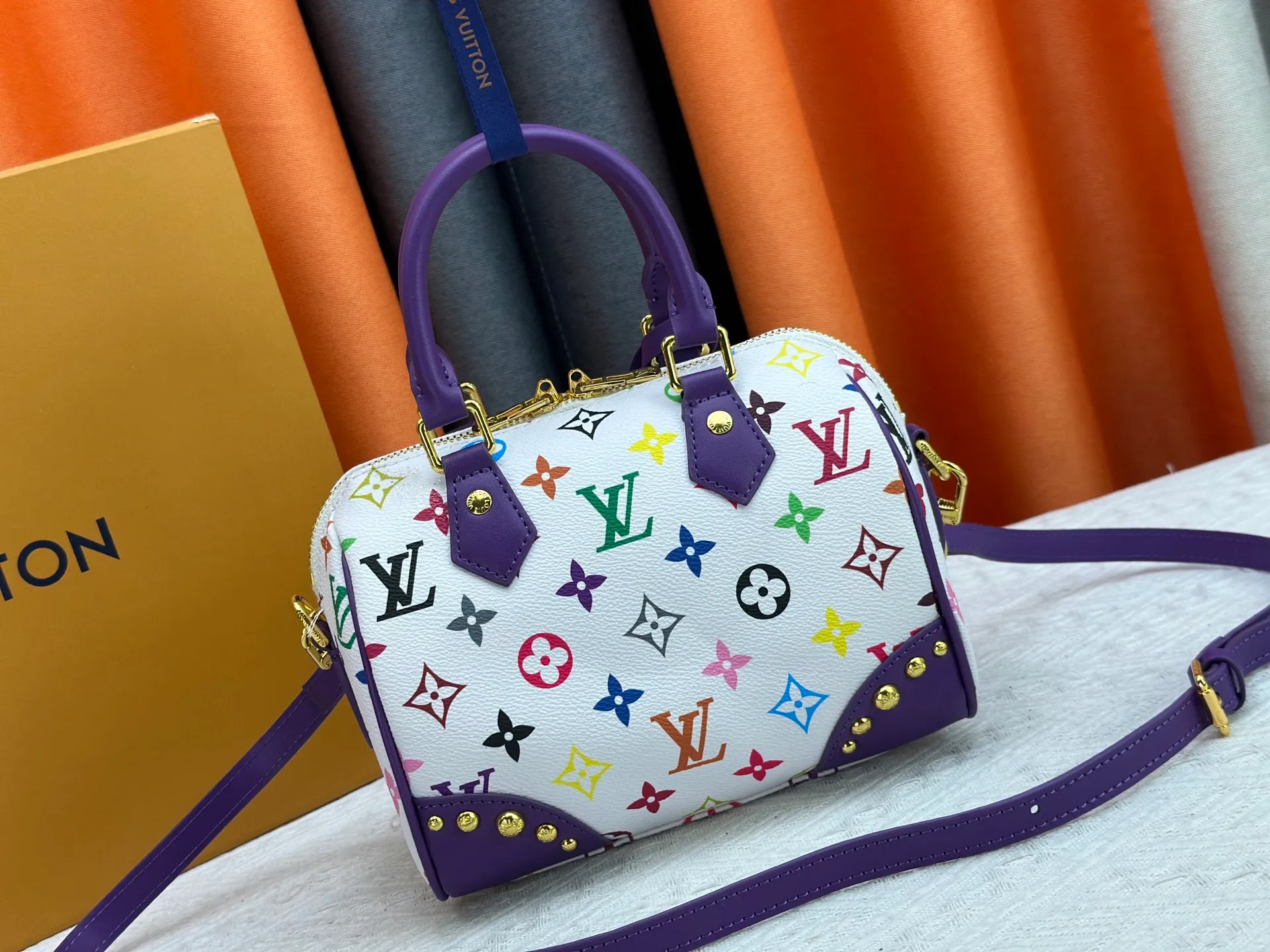 P260 upgraded original M58953 M46234 M46222 Speedy Bandoulière 20 handbag is made of soft coated canvas, and the full-length Monogram pattern is traced in colorful rainbow tones, highlighting the smart style of the Louis Vuitton x Murakami reissue series. The Toron handle and detachable shoulder strap are constructed of cow leather, the metal corners recall classic luggage elements, and the bow-shaped key bag and padlock add brand touches. Dimensions: 20.5 x 13.5 x 12.0 cm (length x height x width)