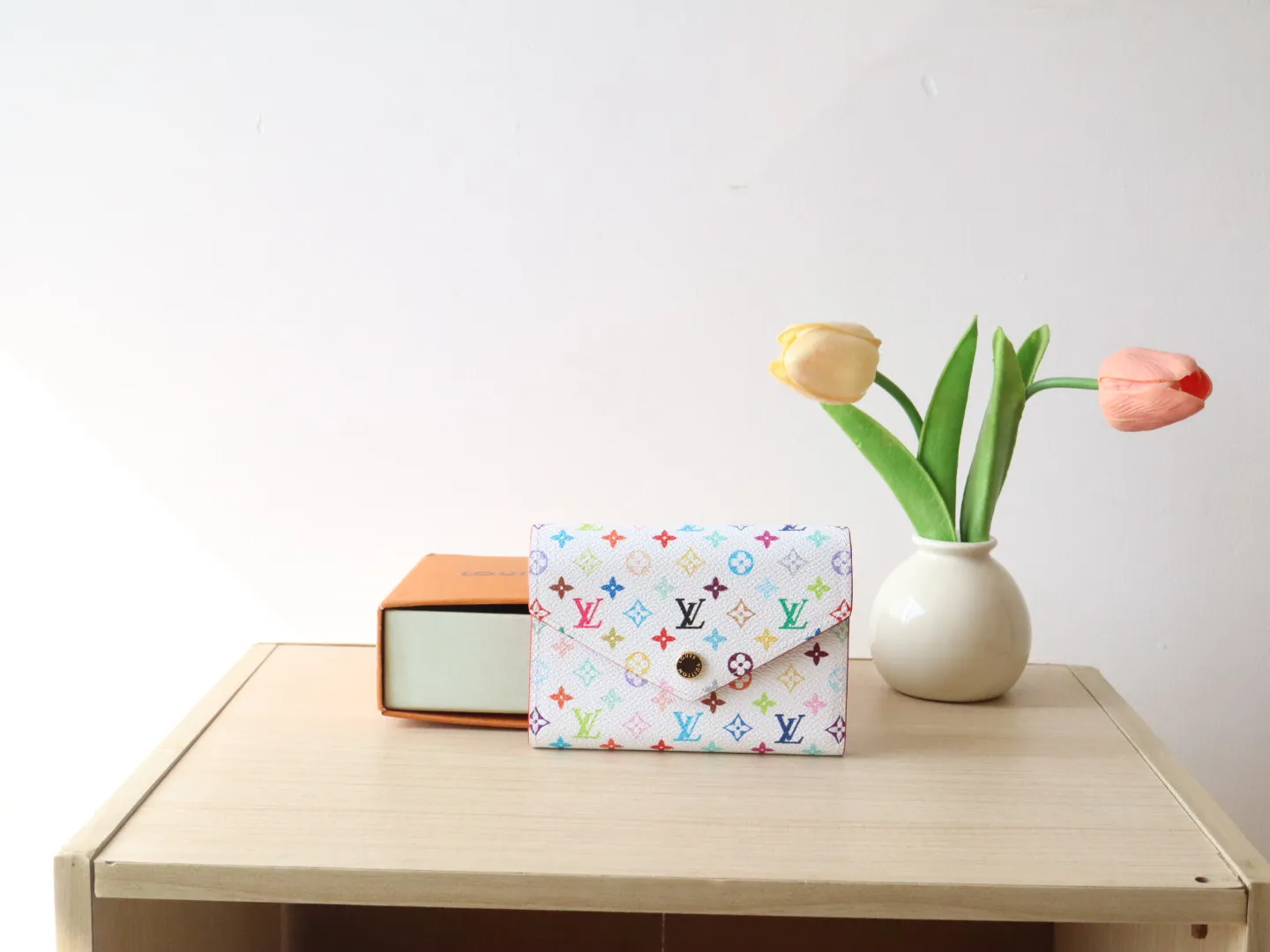 14163 Tri-Color Tri-fold Wallet🌟P90 This replica version of the Victorine wallet from the Louis Vuitton x Murakami series is small and exquisite. The colorful Monogram pattern reinterprets Louis Vuitton's classic logo with the famous rainbow tones of Japanese artist Takashi Murakami. The wallet is made of coated canvas with fine cowhide lining and silver-tone hardware. It has a zippered coin compartment and multiple interior compartments for banknotes and business cards. 12 x 9.5 x 2.5 cm (length x height x width)