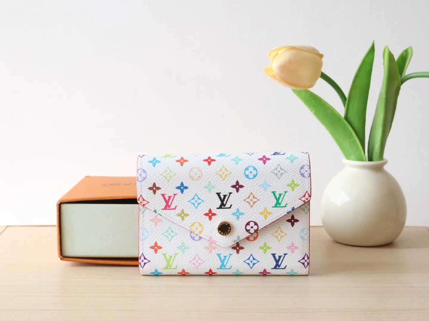 14163 Tri-Color Tri-fold Wallet🌟P90 This replica version of the Victorine wallet from the Louis Vuitton x Murakami series is small and exquisite. The colorful Monogram pattern reinterprets Louis Vuitton's classic logo with the famous rainbow tones of Japanese artist Takashi Murakami. The wallet is made of coated canvas with fine cowhide lining and silver-tone hardware. It has a zippered coin compartment and multiple interior compartments for banknotes and business cards. 12 x 9.5 x 2.5 cm (length x height x width)