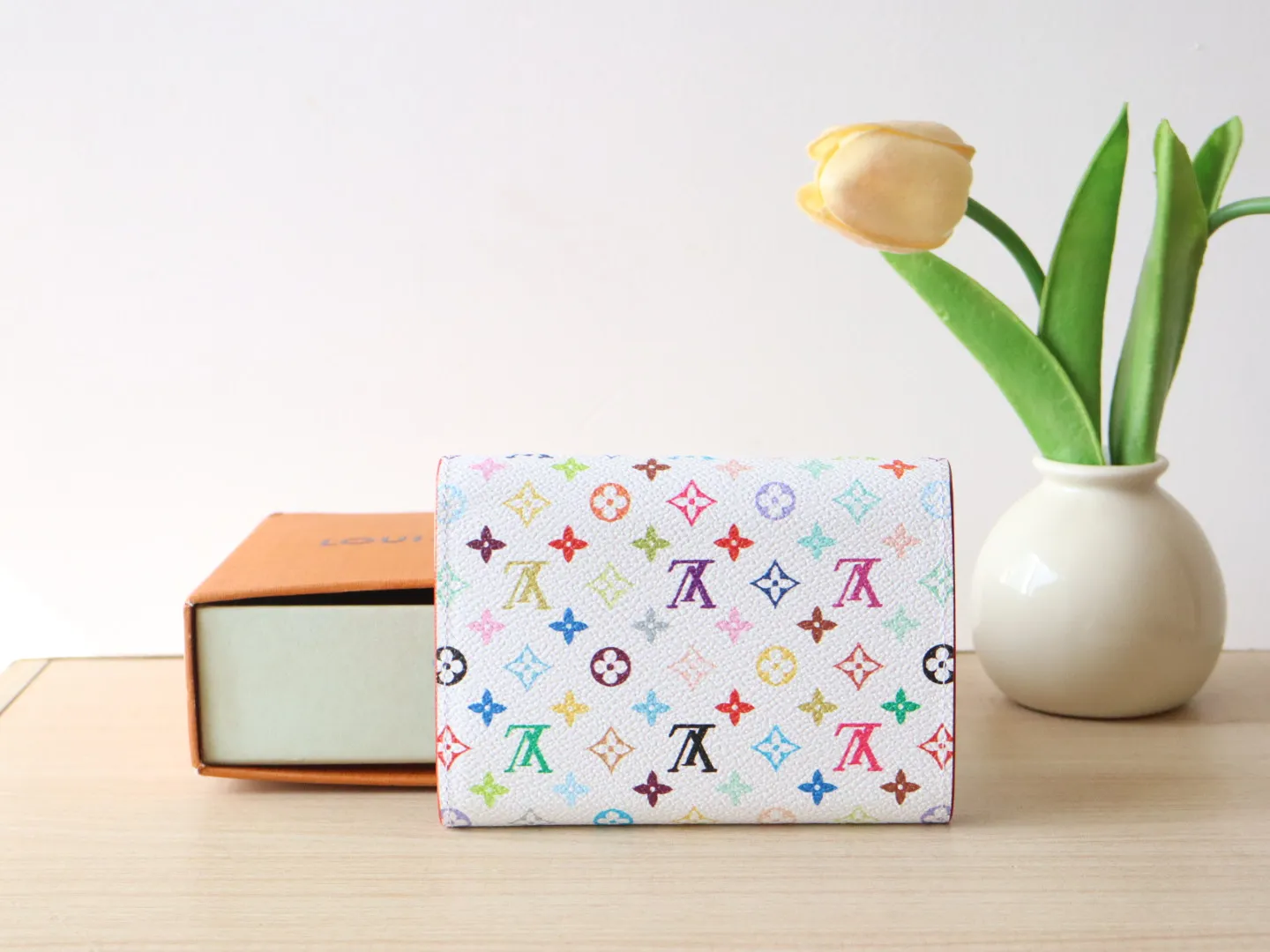 14163 Tri-Color Tri-fold Wallet🌟P90 This replica version of the Victorine wallet from the Louis Vuitton x Murakami series is small and exquisite. The colorful Monogram pattern reinterprets Louis Vuitton's classic logo with the famous rainbow tones of Japanese artist Takashi Murakami. The wallet is made of coated canvas with fine cowhide lining and silver-tone hardware. It has a zippered coin compartment and multiple interior compartments for banknotes and business cards. 12 x 9.5 x 2.5 cm (length x height x width)