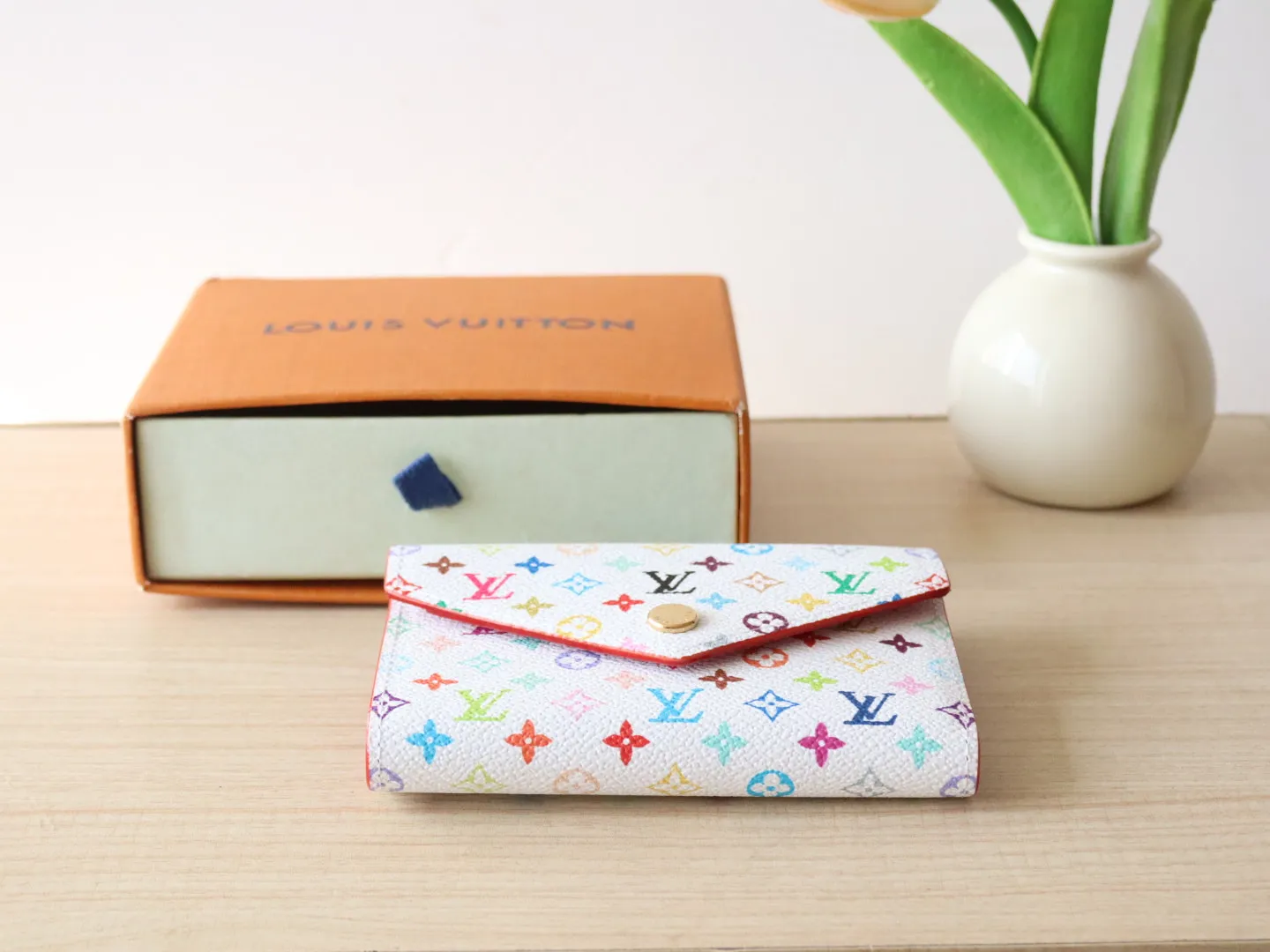14163 Tri-Color Tri-fold Wallet🌟P90 This replica version of the Victorine wallet from the Louis Vuitton x Murakami series is small and exquisite. The colorful Monogram pattern reinterprets Louis Vuitton's classic logo with the famous rainbow tones of Japanese artist Takashi Murakami. The wallet is made of coated canvas with fine cowhide lining and silver-tone hardware. It has a zippered coin compartment and multiple interior compartments for banknotes and business cards. 12 x 9.5 x 2.5 cm (length x height x width)