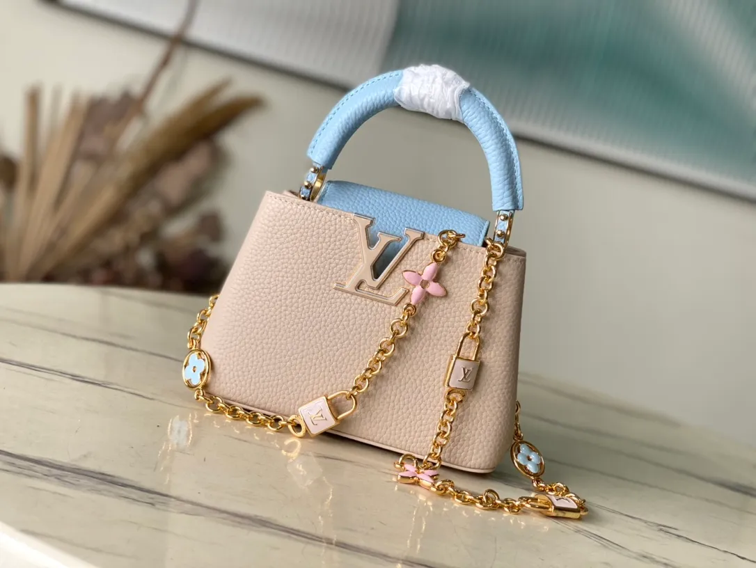 💰2200 (Special grade original leather) M23952 mini This Capucines mini handbag comes from the Lovelock Chain series. The Taurillon leather bag has a dotted rope that looks like a jewelry chain, with a padlock and pastel enamel Monogram flowers, echoing the dual tones of the leather. The detachable chain and top handle provide more carrying options, and the inner pocket is equipped with a small mirror for easy touch-ups at any time. Dimensions: 21 × 14 × 8 cm