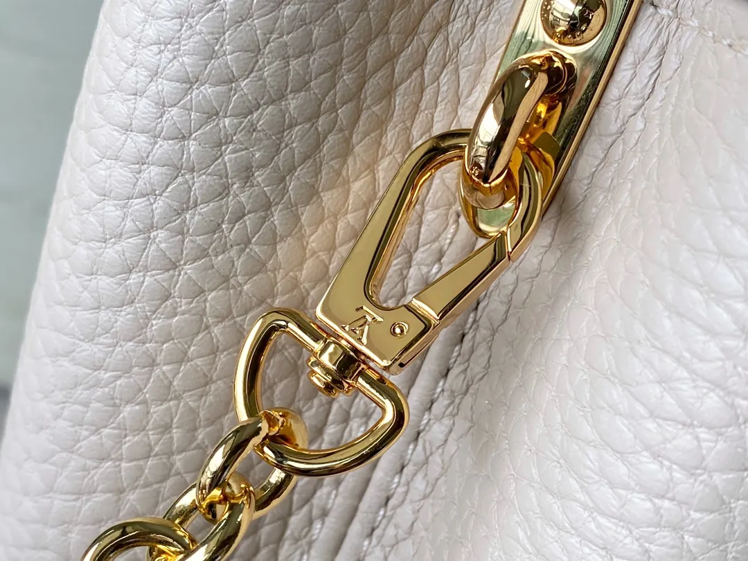 💰2200 (Special grade original leather) M23952 mini This Capucines mini handbag comes from the Lovelock Chain series. The Taurillon leather bag has a dotted rope that looks like a jewelry chain, with a padlock and pastel enamel Monogram flowers, echoing the dual tones of the leather. The detachable chain and top handle provide more carrying options, and the inner pocket is equipped with a small mirror for easy touch-ups at any time. Dimensions: 21 × 14 × 8 cm