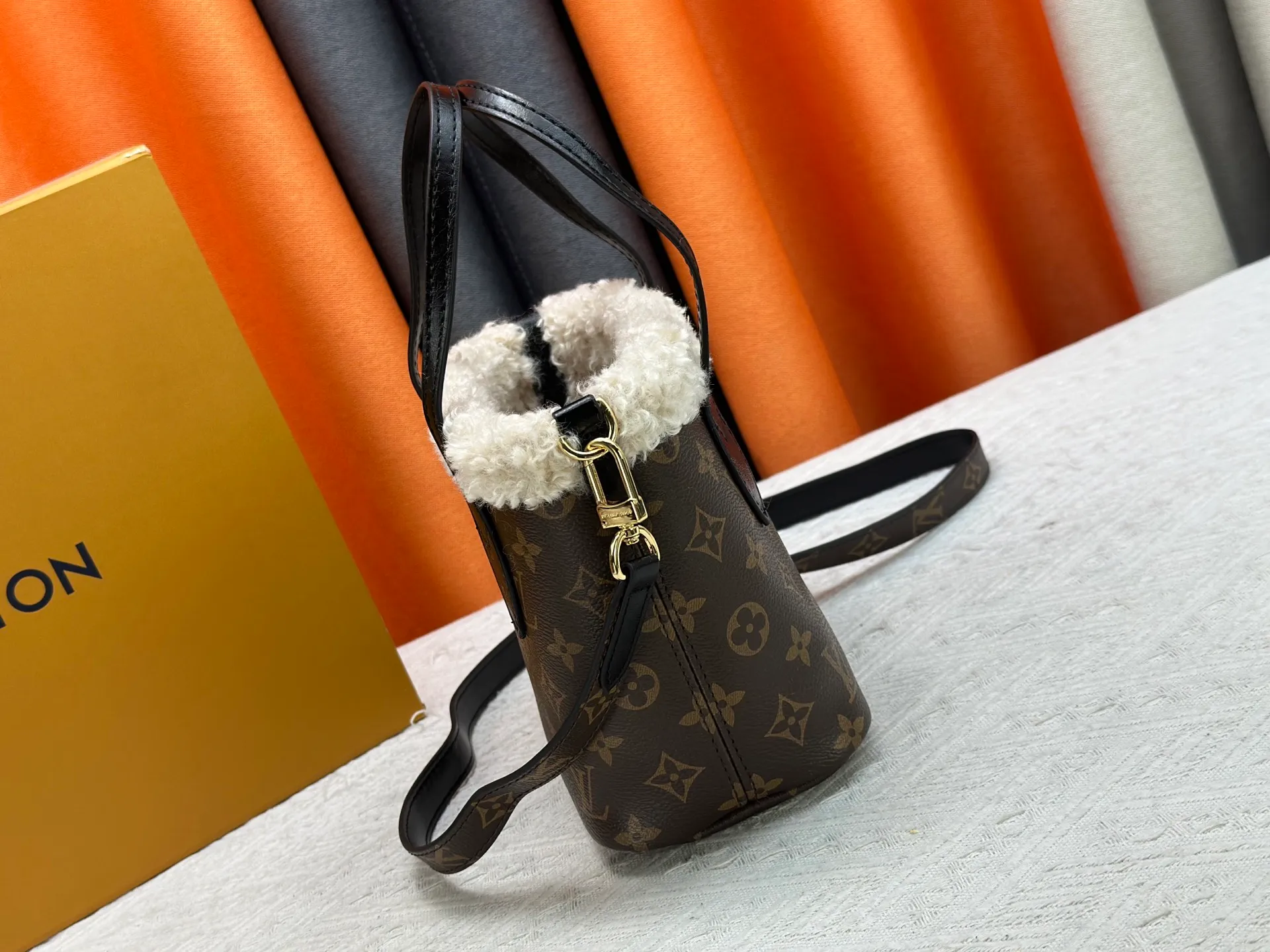 P340M26315 12099 Guangzhou upgraded version This Neverfull Bandoulière Inside Out BB handbag comes from the LV Ski series and is made of Monogram canvas with trendy shearling trim and lining. The Teddygram logo is laid out on it, creating a sophisticated style with dazzling metal parts. A zippered pocket adds a finishing touch to the reversible design, allowing it to be held individually. Long shoulder straps allow for cross-body comfort. 16.5 x 11 x 26.5 cm (height x width x length)