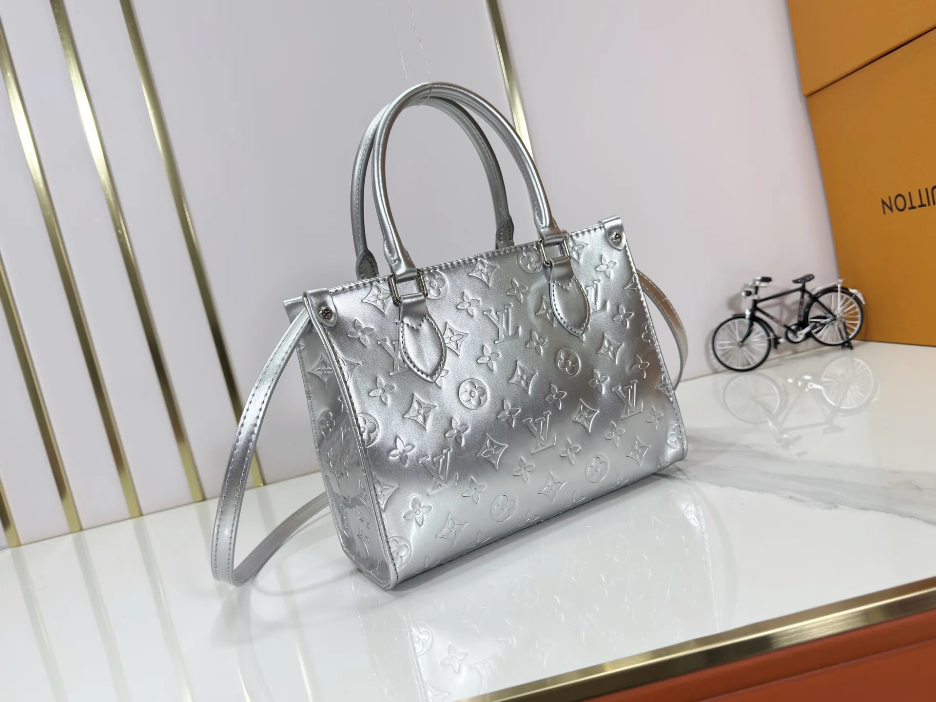 P220 upgraded original M26373 M45659 M44571 This OnTheGo small handbag joins the LV Ski series in the Monogram Miroir version. Laminated canvas ensures durability. Silver hues and tonal hardware create a gleaming look. Built-in pockets can store daily necessities such as small books. Dimensions: 25 x 19 x 11.5 (cm) ((length x height x width)