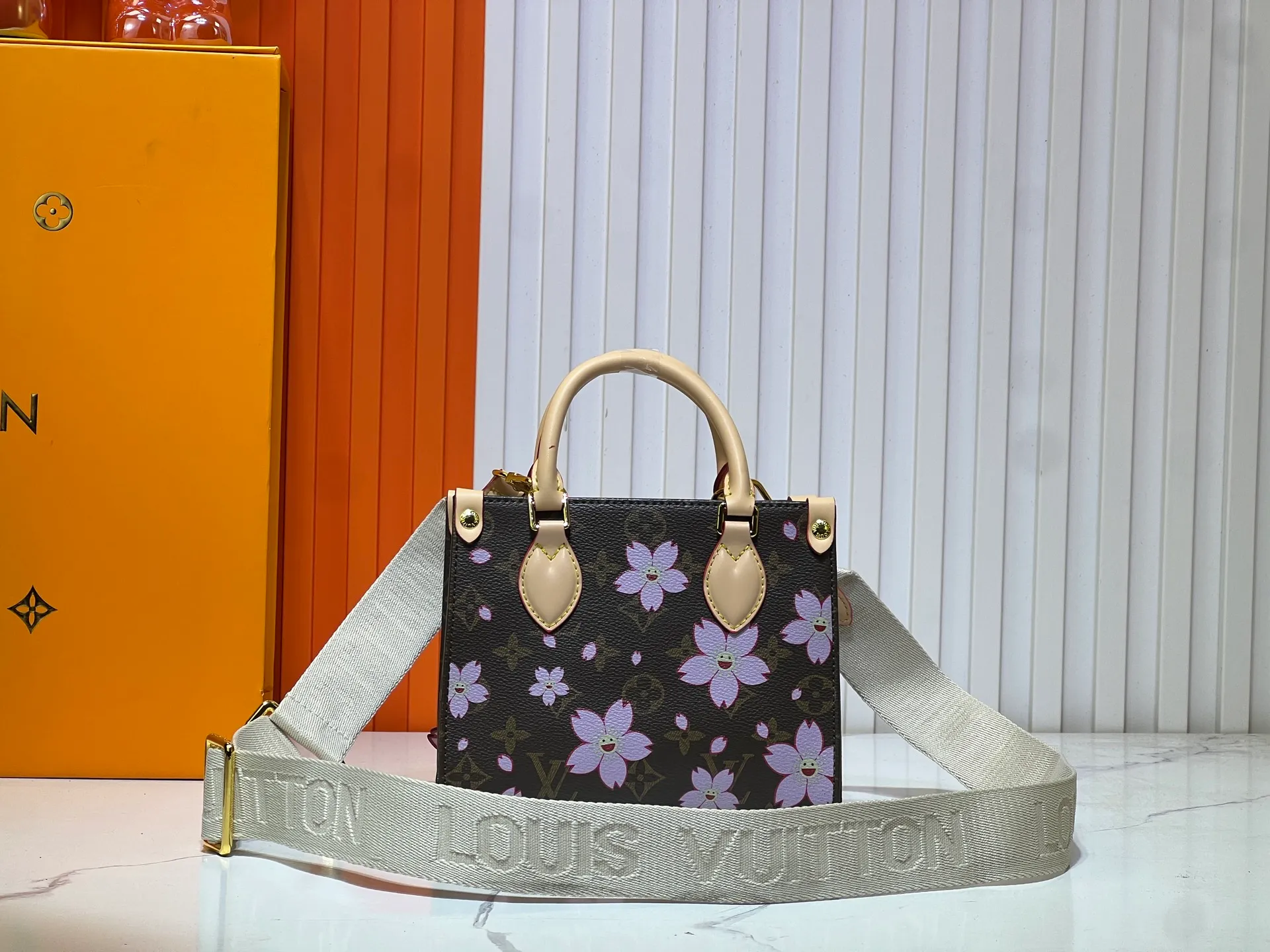 Batch 300💰M45659 M46373🔥Lv&Takashi Murakami🐼Sakura🌸OnTheGo small new version The legendary ONTHEGO handbag: always able to meet your various needs for handbags. It has a large capacity but is not bulky. It is stiff and soft to the touch, making it suitable for home and travel. Tighten the side ties and it instantly transforms into a stylish urban handbag. Loosen the straps and it transforms into a chic and practical handbag. The slender leather handle can be carried over the shoulder or between the arms. The model shown here is made of Damier Azur canvas. Size: 18x15x8.5cm