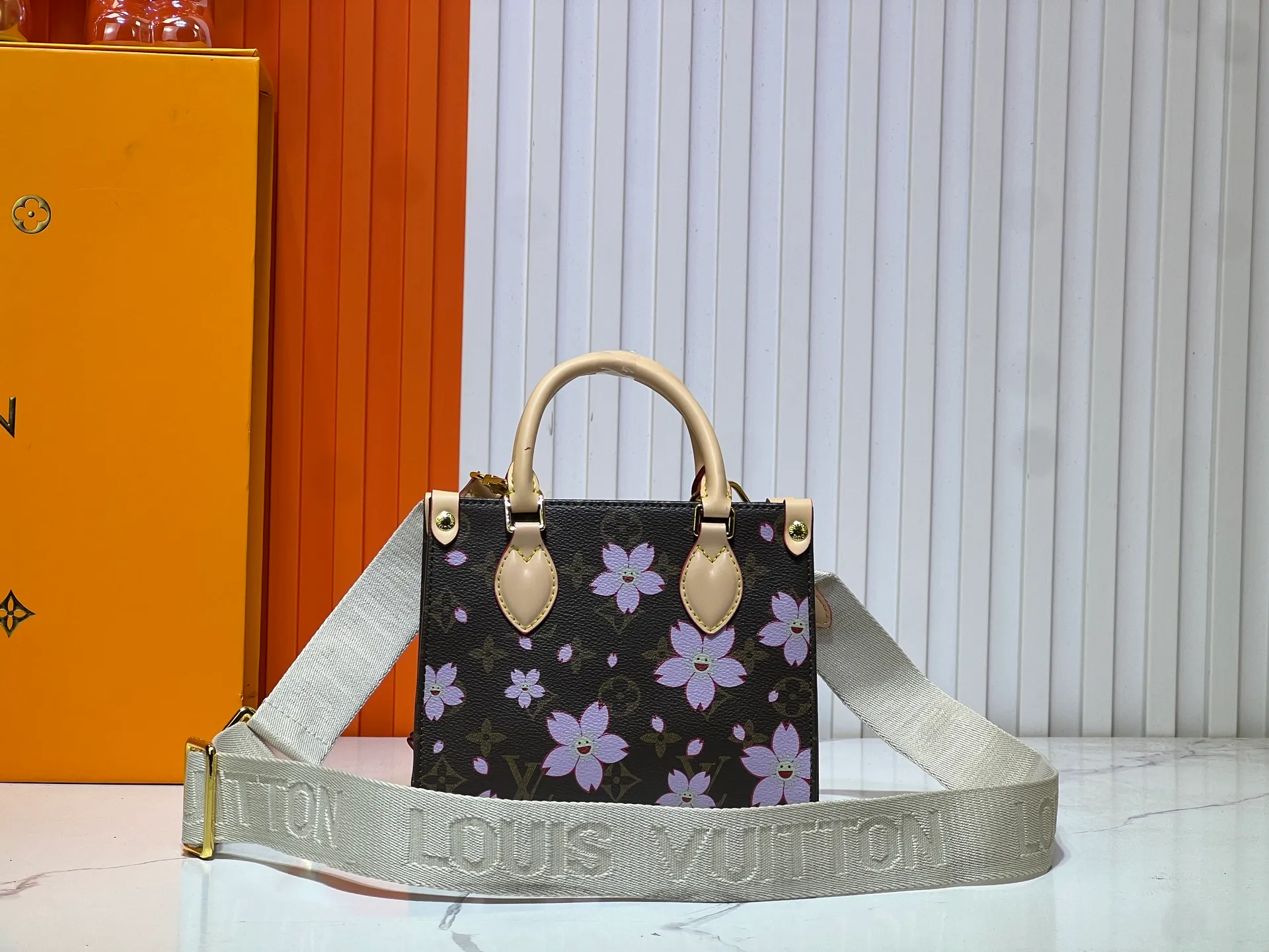 Batch 300💰M45659 M46373🔥Lv&Takashi Murakami🐼Sakura🌸OnTheGo small new version The legendary ONTHEGO handbag: always able to meet your various needs for handbags. It has a large capacity but is not bulky. It is stiff and soft to the touch, making it suitable for home and travel. Tighten the side ties and it instantly transforms into a stylish urban handbag. Loosen the straps and it transforms into a chic and practical handbag. The slender leather handle can be carried over the shoulder or between the arms. The model shown here is made of Damier Azur canvas. Size: 18x15x8.5cm