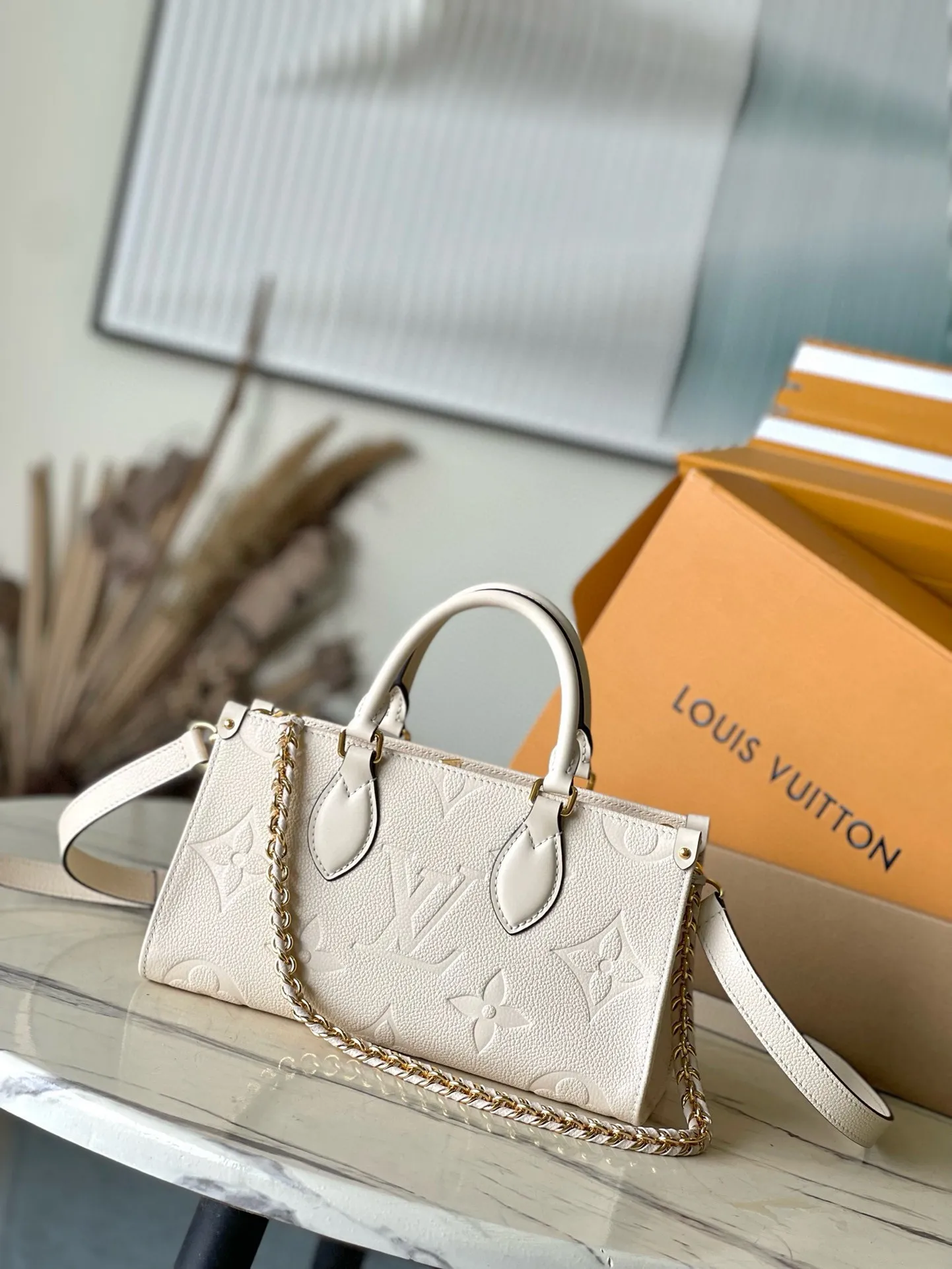 💰1100 (top layer leather) top original order M23698 off-white This small OnTheGo handbag is made of Monogram Empreinte leather embossed with Giant Monogram pattern, highlighting the soft and slender silhouette. The compact interior keeps your daily essentials organized, while the articulated top handle and detachable leather and woven chain shoulder strap allow for a variety of carrying options. Dimensions: 25 × 13 × 10 cm
