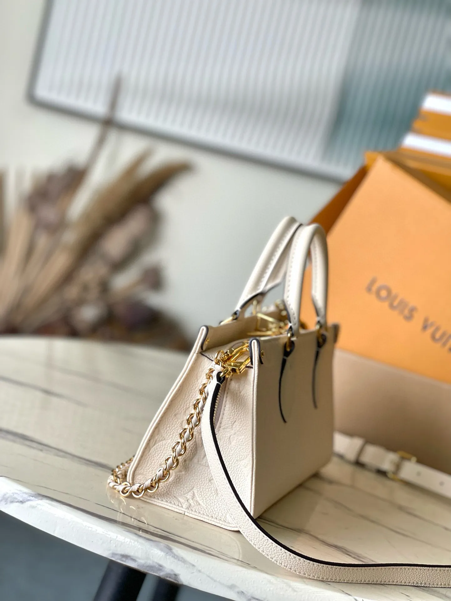 💰1100 (top layer leather) top original order M23698 off-white This small OnTheGo handbag is made of Monogram Empreinte leather embossed with Giant Monogram pattern, highlighting the soft and slender silhouette. The compact interior keeps your daily essentials organized, while the articulated top handle and detachable leather and woven chain shoulder strap allow for a variety of carrying options. Dimensions: 25 × 13 × 10 cm