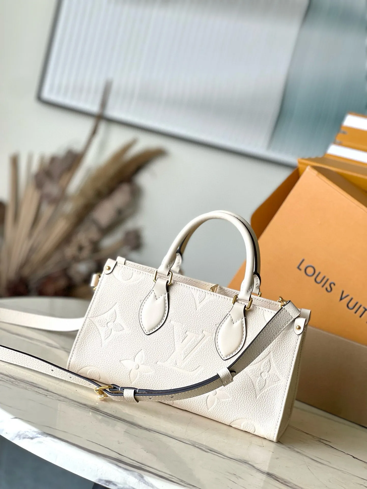 💰1100 (top layer leather) top original order M23698 off-white This small OnTheGo handbag is made of Monogram Empreinte leather embossed with Giant Monogram pattern, highlighting the soft and slender silhouette. The compact interior keeps your daily essentials organized, while the articulated top handle and detachable leather and woven chain shoulder strap allow for a variety of carrying options. Dimensions: 25 × 13 × 10 cm