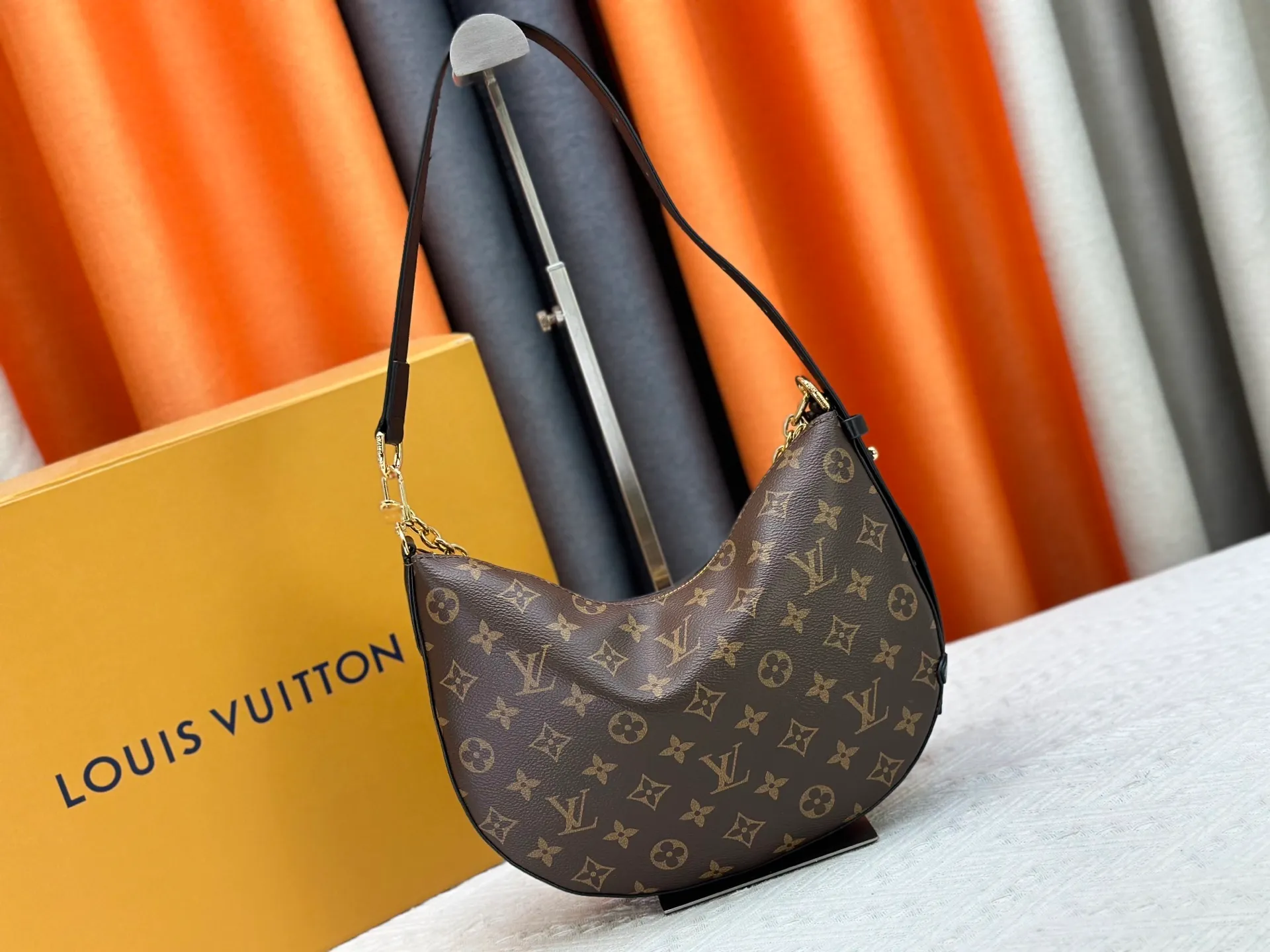 P240 Upgraded original M15056 This Cookie BB handbag is made of Monogram coated canvas, with contrasting leather trim to highlight the half-moon shape. The lightweight design combines an adjustable handle and a detachable chain to allow for easy conversion between cross-body and shoulder wear. The two ends of the bag can be connected to create a trendy wrist bag look. Dimensions: 28.5 x 19.0 x 5.0 cm (length x height x width)
