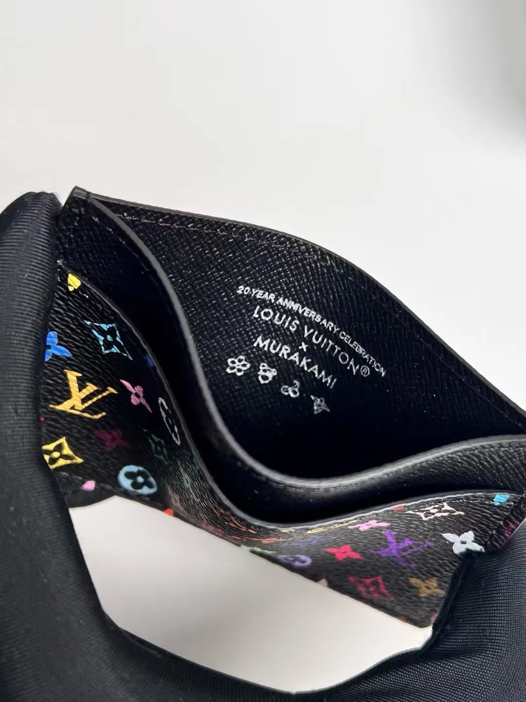 p100 M13403 Black color! LV x TM business card holder, this re-engraved version of the classic business card holder from the Louis Vuitton x Murakami collaboration series is reinterpreted in playful rainbow tones. Made of coated canvas, the classic Monogram pattern is designed in the extremely bright and iconic colors of Japanese artist Takashi Murakami, and the top is decorated with a bright pink color. The interior of the business card holder is suitable for large business cards and receipts, while the exterior features two classic business card compartments.  11 x 7 x 0.5 cm (length x height x width).