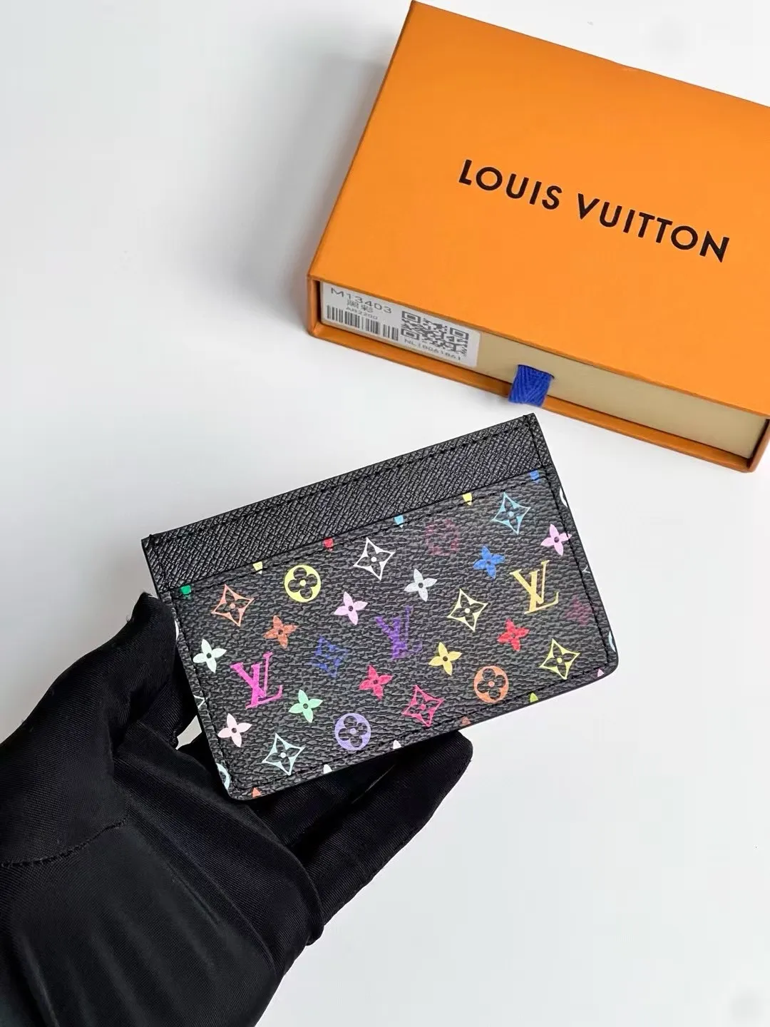 p100 M13403 Black color! LV x TM business card holder, this re-engraved version of the classic business card holder from the Louis Vuitton x Murakami collaboration series is reinterpreted in playful rainbow tones. Made of coated canvas, the classic Monogram pattern is designed in the extremely bright and iconic colors of Japanese artist Takashi Murakami, and the top is decorated with a bright pink color. The interior of the business card holder is suitable for large business cards and receipts, while the exterior features two classic business card compartments.  11 x 7 x 0.5 cm (length x height x width).