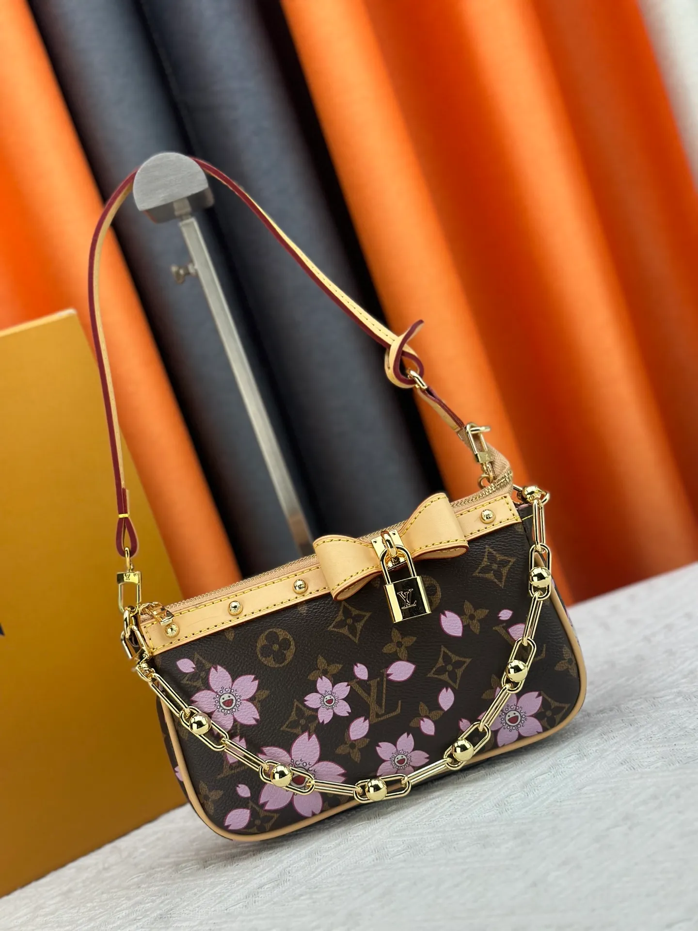 P240 M13666 This Pochette Accessoires handbag is made of classic Monogram canvas with the bright Cherry Blossom pattern written by Takashi Murakami, which brings out the distinctive elements of the Louis Vuitton x Takashi Murakami replica series in a playful style. A leather bow and LV-engraved padlock accentuate the upper edge, while dazzling studs and a detachable chain add a touch of uninhibited style. Monogram coated canvas leather trimmed fabric lining with metal hardware, zipper closure, can store a 6.7-inch smartphone and card holder. The shoulder strap is removable and not adjustable. Size: 22x13x4cm