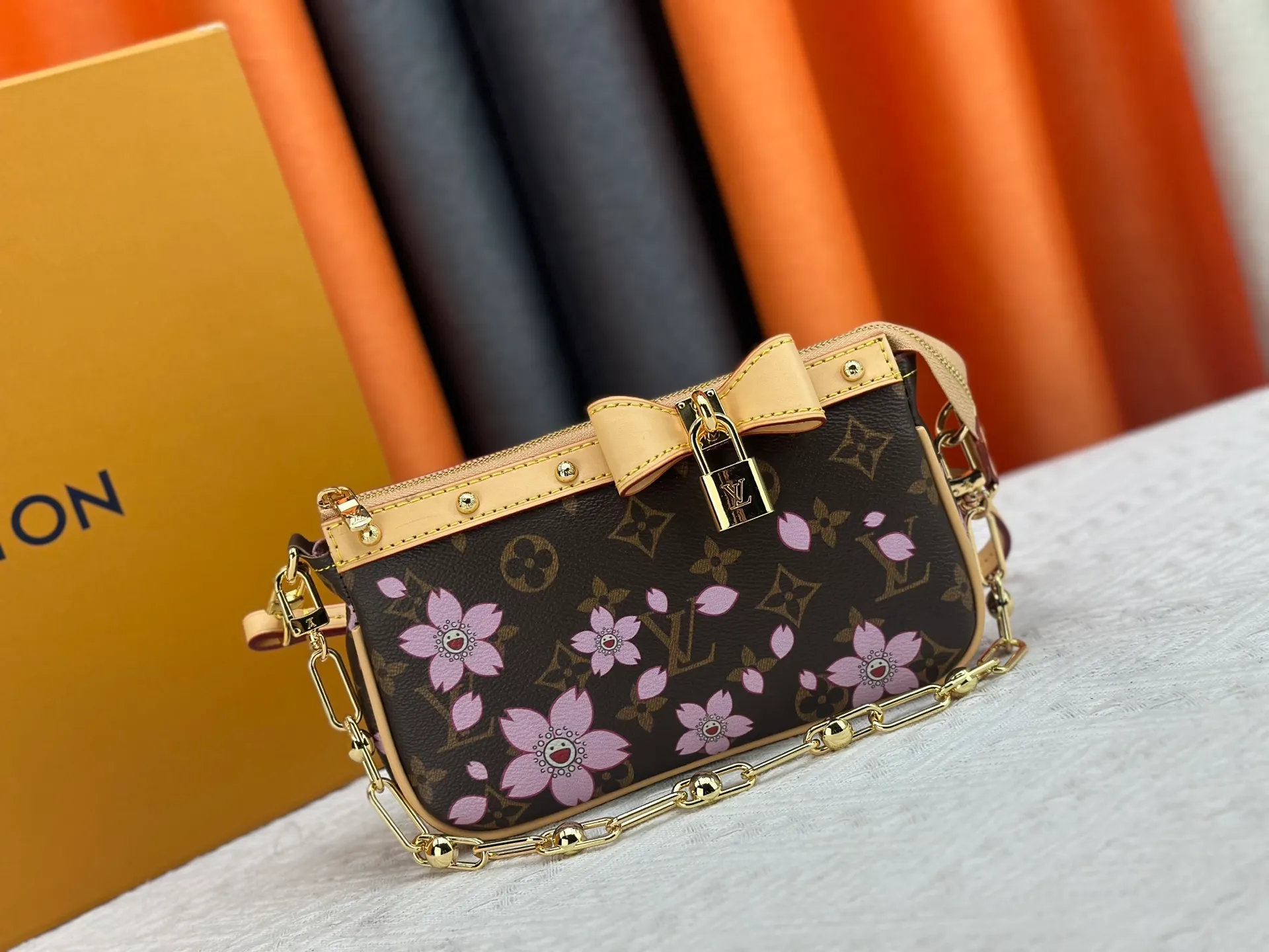 P240 M13666 This Pochette Accessoires handbag is made of classic Monogram canvas with the bright Cherry Blossom pattern written by Takashi Murakami, which brings out the distinctive elements of the Louis Vuitton x Takashi Murakami replica series in a playful style. A leather bow and LV-engraved padlock accentuate the upper edge, while dazzling studs and a detachable chain add a touch of uninhibited style. Monogram coated canvas leather trimmed fabric lining with metal hardware, zipper closure, can store a 6.7-inch smartphone and card holder. The shoulder strap is removable and not adjustable. Size: 22x13x4cm