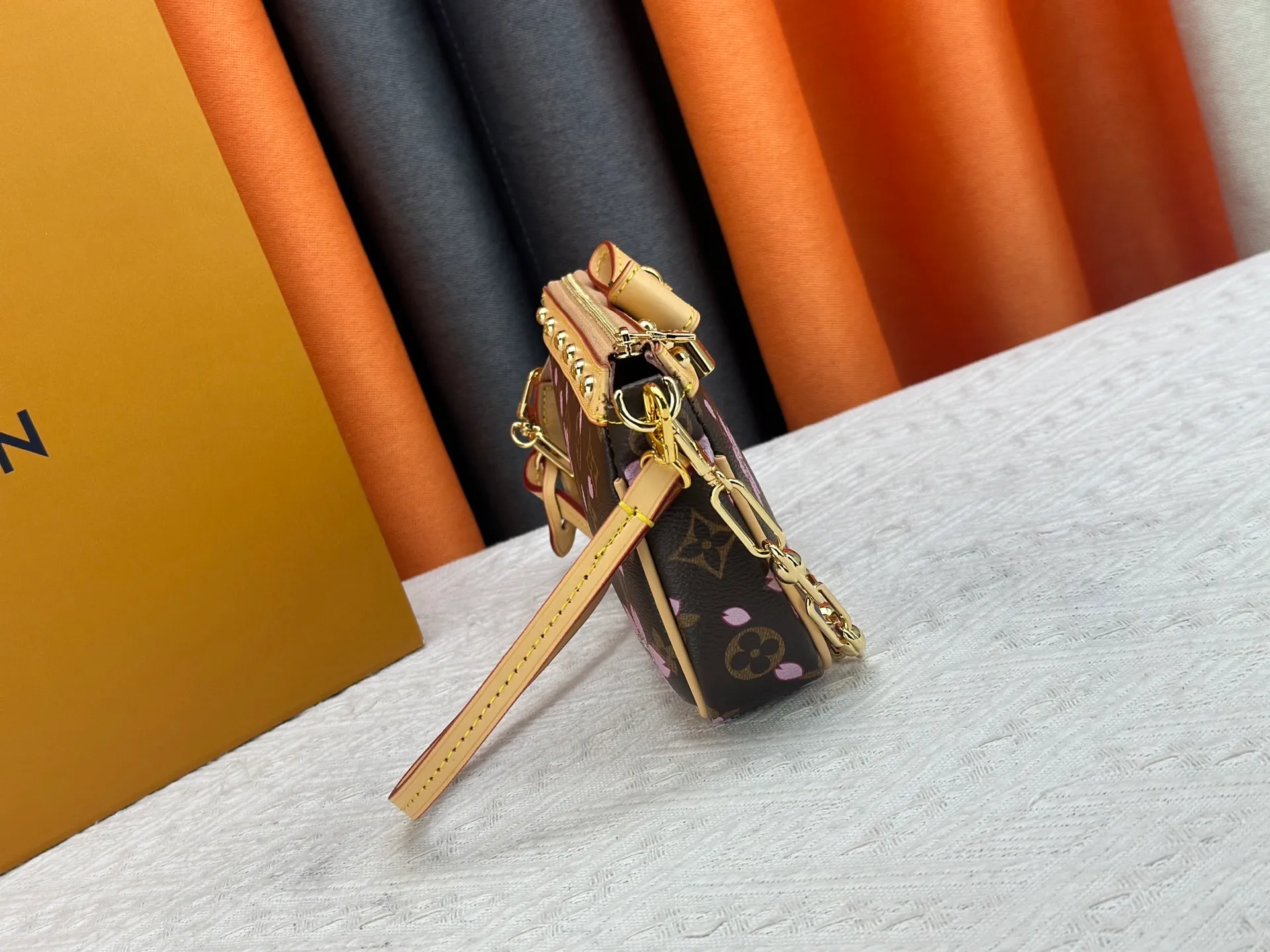 P240 M13666 This Pochette Accessoires handbag is made of classic Monogram canvas with the bright Cherry Blossom pattern written by Takashi Murakami, which brings out the distinctive elements of the Louis Vuitton x Takashi Murakami replica series in a playful style. A leather bow and LV-engraved padlock accentuate the upper edge, while dazzling studs and a detachable chain add a touch of uninhibited style. Monogram coated canvas leather trimmed fabric lining with metal hardware, zipper closure, can store a 6.7-inch smartphone and card holder. The shoulder strap is removable and not adjustable. Size: 22x13x4cm