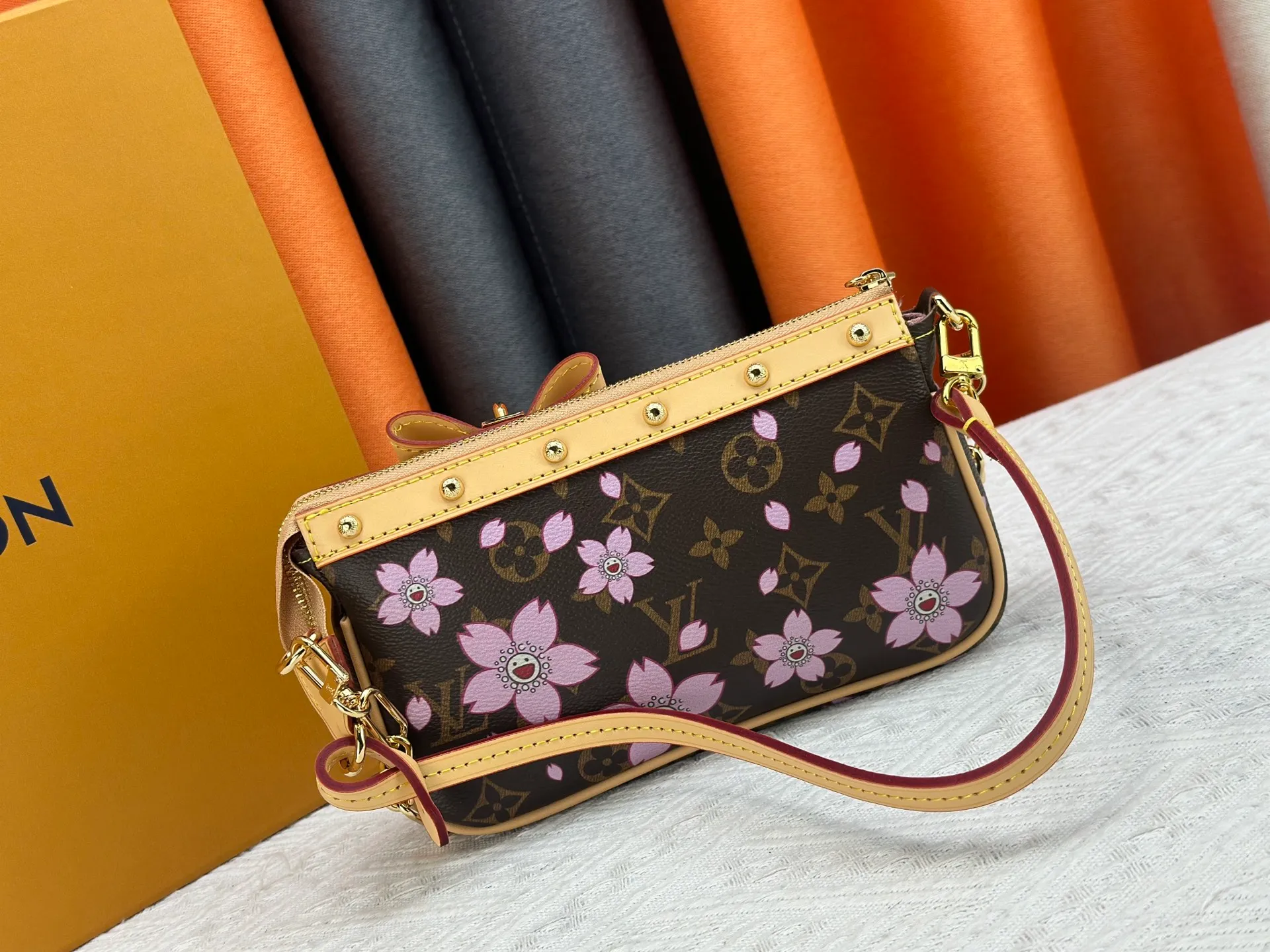 P240 M13666 This Pochette Accessoires handbag is made of classic Monogram canvas with the bright Cherry Blossom pattern written by Takashi Murakami, which brings out the distinctive elements of the Louis Vuitton x Takashi Murakami replica series in a playful style. A leather bow and LV-engraved padlock accentuate the upper edge, while dazzling studs and a detachable chain add a touch of uninhibited style. Monogram coated canvas leather trimmed fabric lining with metal hardware, zipper closure, can store a 6.7-inch smartphone and card holder. The shoulder strap is removable and not adjustable. Size: 22x13x4cm