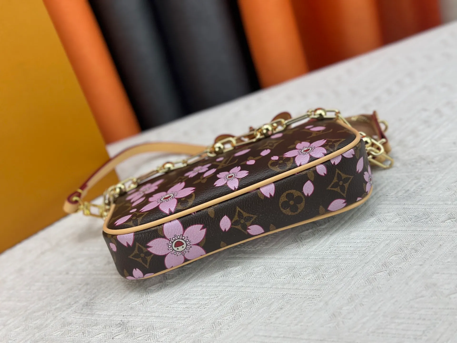 P240 M13666 This Pochette Accessoires handbag is made of classic Monogram canvas with the bright Cherry Blossom pattern written by Takashi Murakami, which brings out the distinctive elements of the Louis Vuitton x Takashi Murakami replica series in a playful style. A leather bow and LV-engraved padlock accentuate the upper edge, while dazzling studs and a detachable chain add a touch of uninhibited style. Monogram coated canvas leather trimmed fabric lining with metal hardware, zipper closure, can store a 6.7-inch smartphone and card holder. The shoulder strap is removable and not adjustable. Size: 22x13x4cm