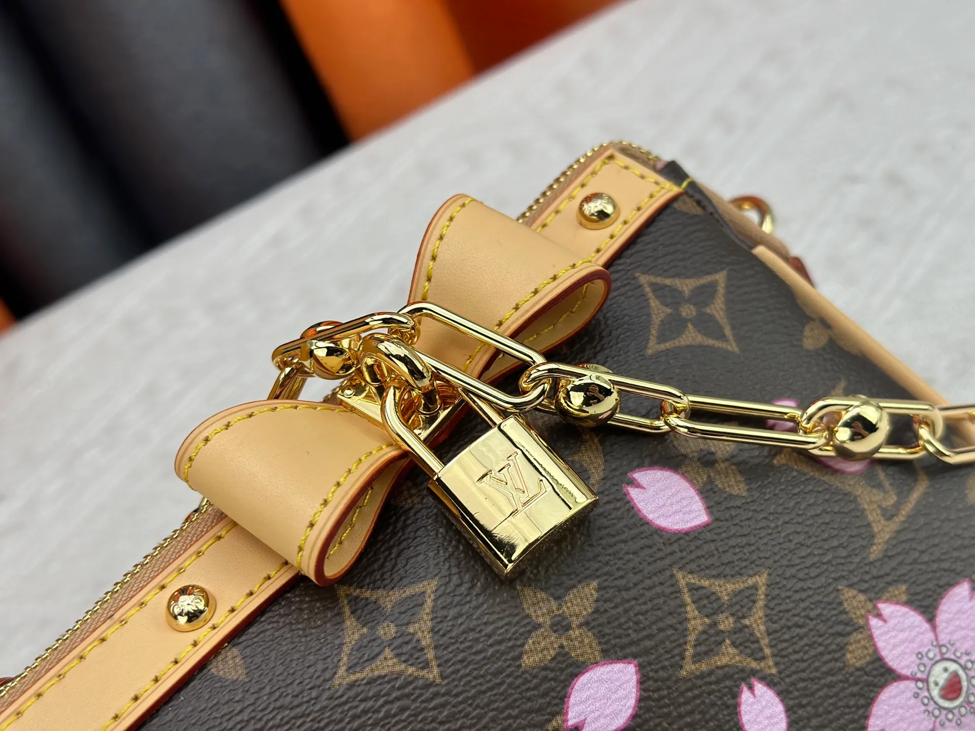 P240 M13666 This Pochette Accessoires handbag is made of classic Monogram canvas with the bright Cherry Blossom pattern written by Takashi Murakami, which brings out the distinctive elements of the Louis Vuitton x Takashi Murakami replica series in a playful style. A leather bow and LV-engraved padlock accentuate the upper edge, while dazzling studs and a detachable chain add a touch of uninhibited style. Monogram coated canvas leather trimmed fabric lining with metal hardware, zipper closure, can store a 6.7-inch smartphone and card holder. The shoulder strap is removable and not adjustable. Size: 22x13x4cm