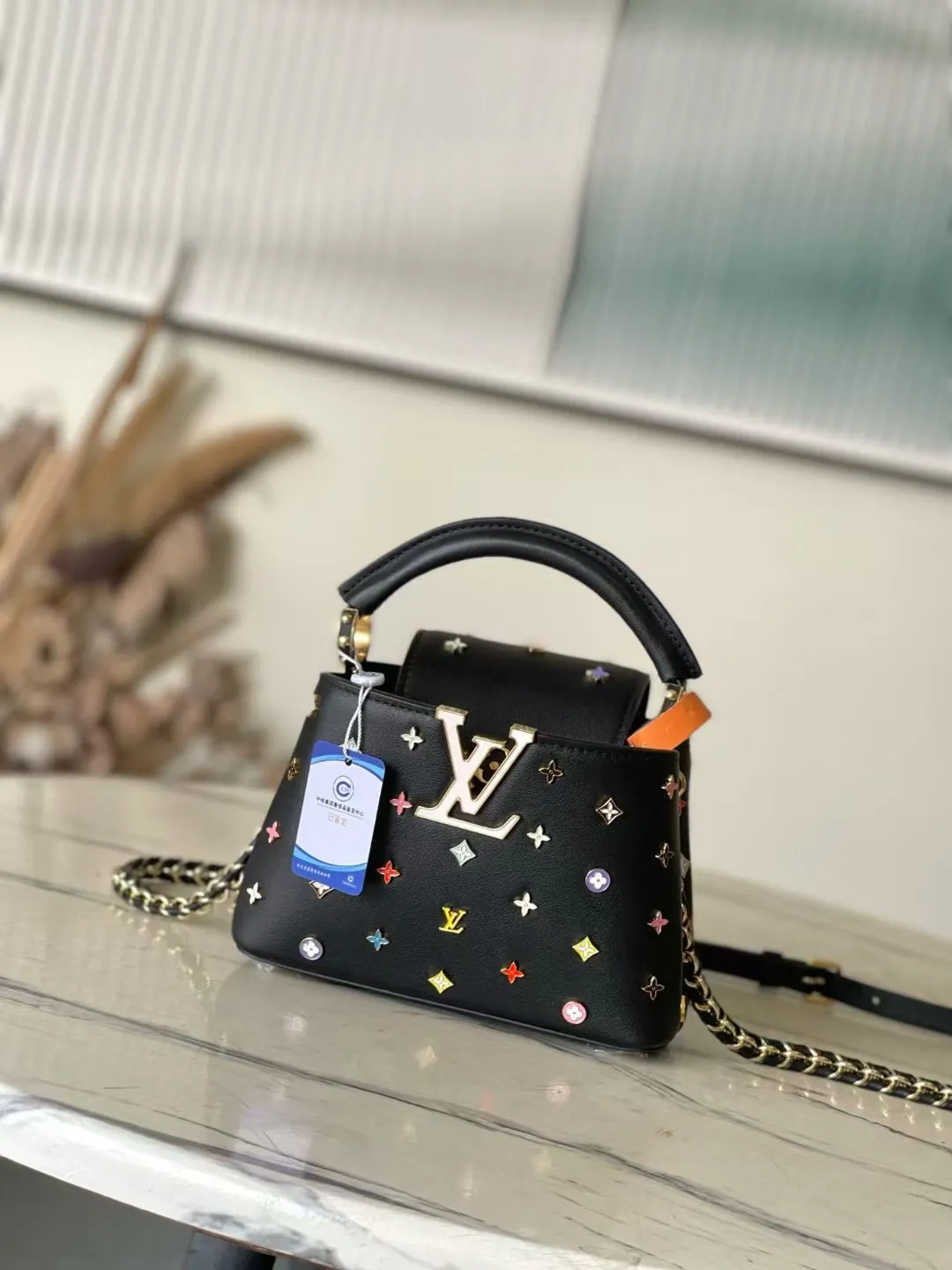 💰2740 "Special Original Leather" M14165 Black This Capucines handbag comes from the Louis Vuitton x Murakami reissue series, using Taurillon cow leather to interpret the classic design in a fun way. The LV lettering and detachable Monogram strap are dipped in bright hues, a nod to the artist's signature iridescent brushwork. The bow-shaped key holder and padlock decoration add sophisticated details, and the interior compartments and multiple pockets can easily store your daily needs. 21.0 x 13.5 x 8.0 cm (L x H x W) • Taurillon cow leather • Cow leather trim • Cow leather lining • Metal hardware • Flap can be placed on the inside or outside • Internal compartment • Internal zip pocket • Internal patch pocket • Key holder • Padlock • Metal base stud