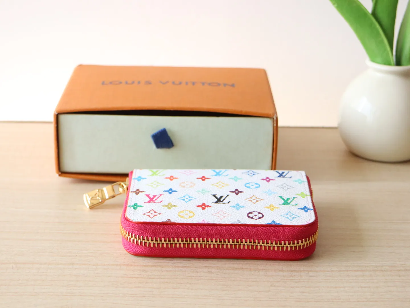 13409 Tricolor Short Zipper Style 🌟P88 LV x TM Zippy Coin Purse M13409 White Color (Tricolor - Murakami) As part of the Louis Vuitton x Murakami series reissue, the timeless Zippy coin purse is practical and playful, upgraded for this season. It's made from Monogram coated canvas in a cheerful rainbow of hues, in keeping with the Japanese artist's signature pop palette. The interior is secured with a silver zipper and is divided into multiple compartments for coins, banknotes and cards. Dimensions: 11 x 8.5 x 2 cm.