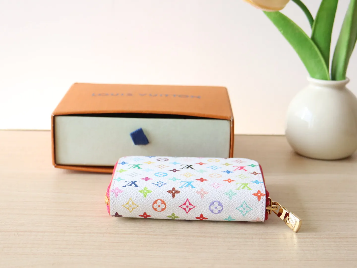 13409 Tricolor Short Zipper Style 🌟P88 LV x TM Zippy Coin Purse M13409 White Color (Tricolor - Murakami) As part of the Louis Vuitton x Murakami series reissue, the timeless Zippy coin purse is practical and playful, upgraded for this season. It's made from Monogram coated canvas in a cheerful rainbow of hues, in keeping with the Japanese artist's signature pop palette. The interior is secured with a silver zipper and is divided into multiple compartments for coins, banknotes and cards. Dimensions: 11 x 8.5 x 2 cm.