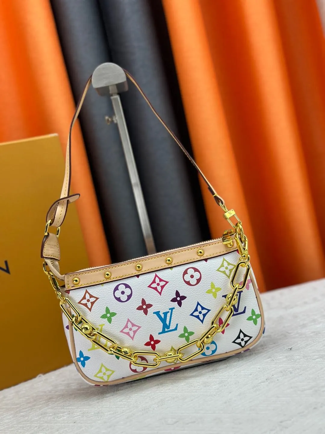 P220 M13404 M13663 Black color White color This Pochette Accessoires handbag is made of coated canvas, with colorful Monogram patterns to interpret the smart style of the Louis Vuitton × Murakami cross-border collaboration series. Calf leather trim and dazzling hardware add to the sophisticated details, while the detachable shoulder strap and chain provide flexible carry. Size: 22x13x4cm
