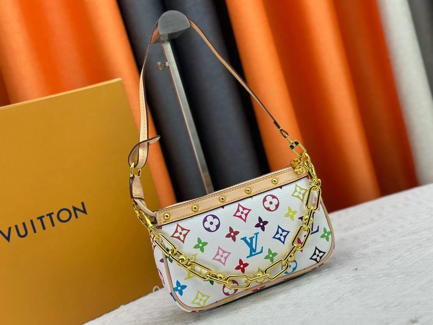 P220 M13404 M13663 Black color White color This Pochette Accessoires handbag is made of coated canvas, with colorful Monogram patterns to interpret the smart style of the Louis Vuitton × Murakami cross-border collaboration series. Calf leather trim and dazzling hardware add to the sophisticated details, while the detachable shoulder strap and chain provide flexible carry. Size: 22x13x4cm