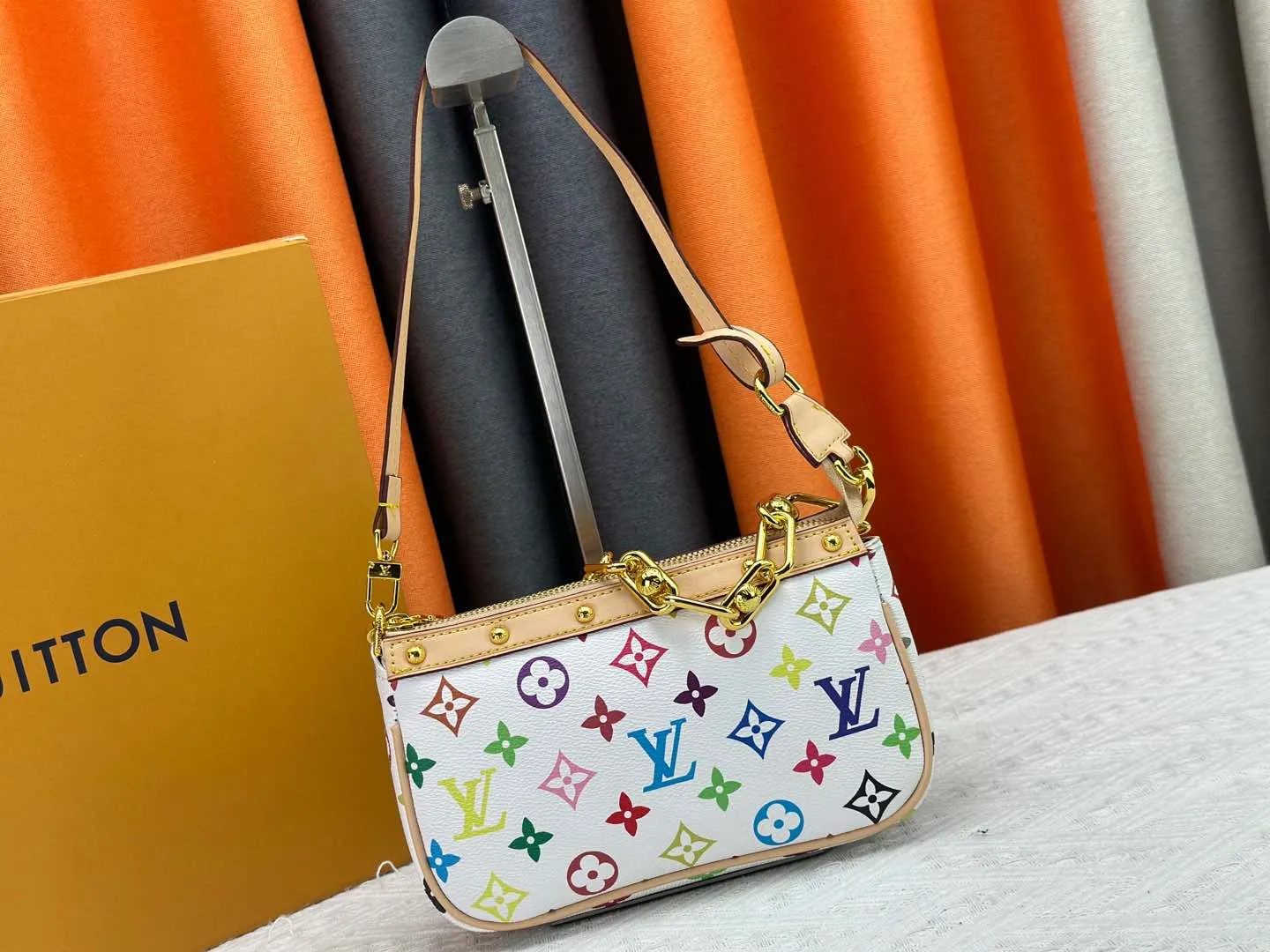 P220 M13404 M13663 Black color White color This Pochette Accessoires handbag is made of coated canvas, with colorful Monogram patterns to interpret the smart style of the Louis Vuitton × Murakami cross-border collaboration series. Calf leather trim and dazzling hardware add to the sophisticated details, while the detachable shoulder strap and chain provide flexible carry. Size: 22x13x4cm
