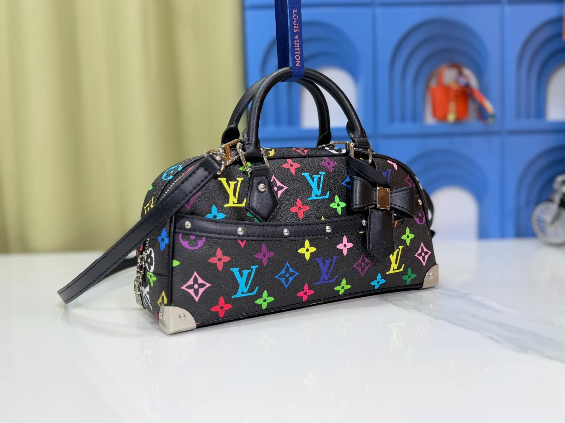 P300 Upgraded Original M13084 This Handbag East West handbag is from the Louis Vuitton x Takashi Murakami reissue series, using the artist's signature rainbow tones to trace the full-length Monogram pattern. Sleek horizontal construction lines the top handle, studded side straps, detachable and adjustable shoulder strap and LV x TM key holder, with cowhide leather details and sophisticated corners that nod to the brand's traditional luggage. Dimensions: 27.0 x 14.0 x 10.0 cm (length x height x width)