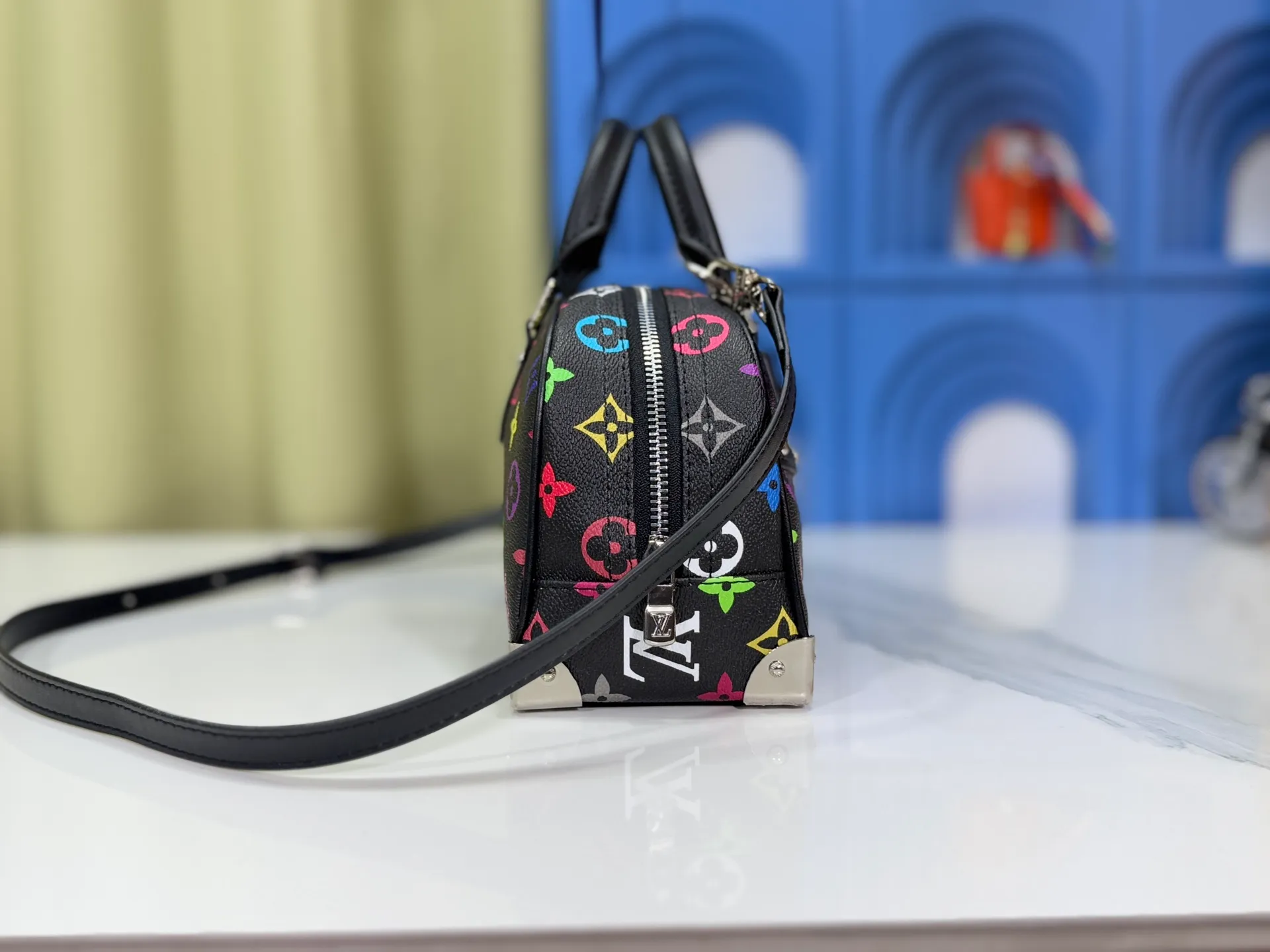 P300 Upgraded Original M13084 This Handbag East West handbag is from the Louis Vuitton x Takashi Murakami reissue series, using the artist's signature rainbow tones to trace the full-length Monogram pattern. Sleek horizontal construction lines the top handle, studded side straps, detachable and adjustable shoulder strap and LV x TM key holder, with cowhide leather details and sophisticated corners that nod to the brand's traditional luggage. Dimensions: 27.0 x 14.0 x 10.0 cm (length x height x width)